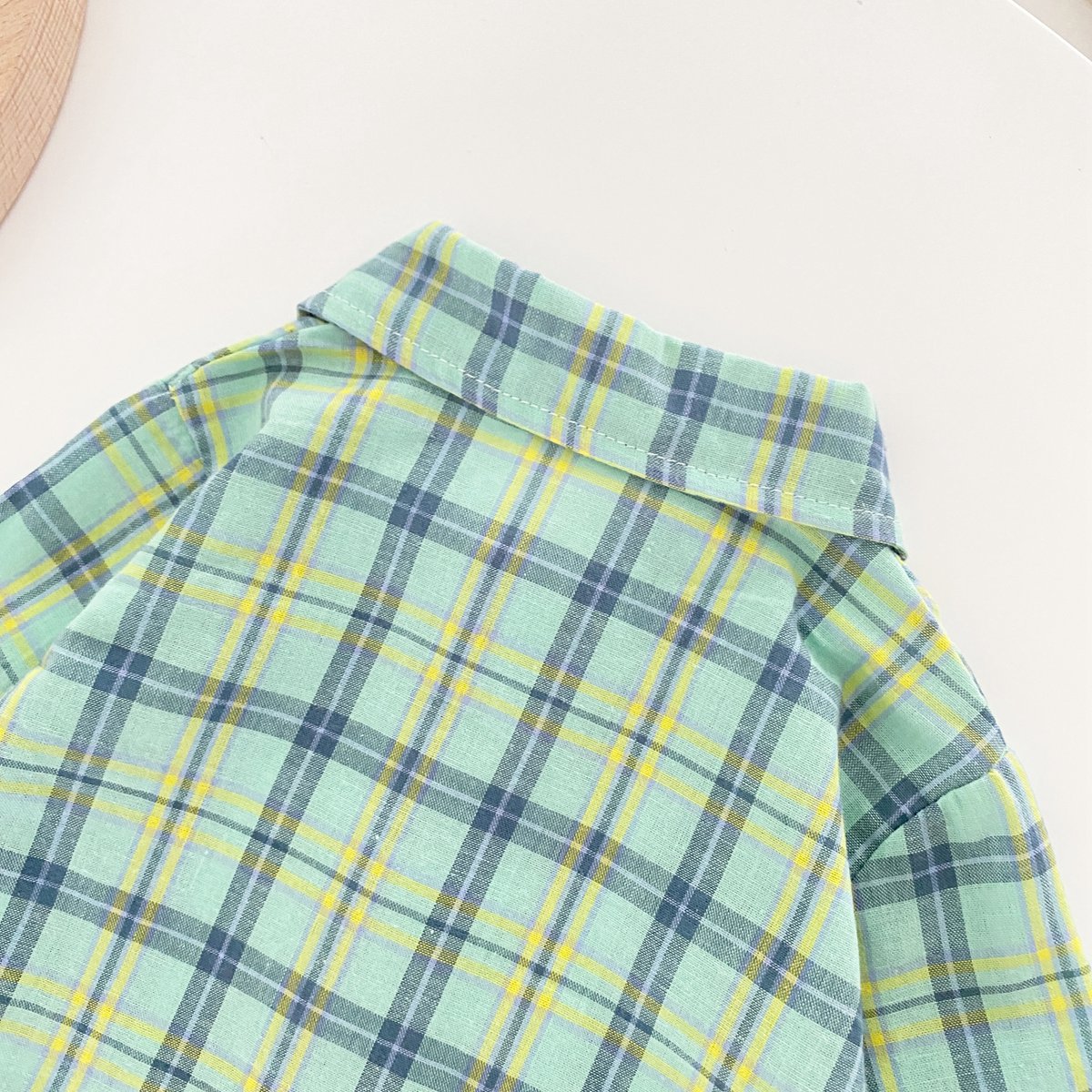 Baby boy wearing a classic plaid pattern long sleeve romper with lapel design in green and apricot colors.