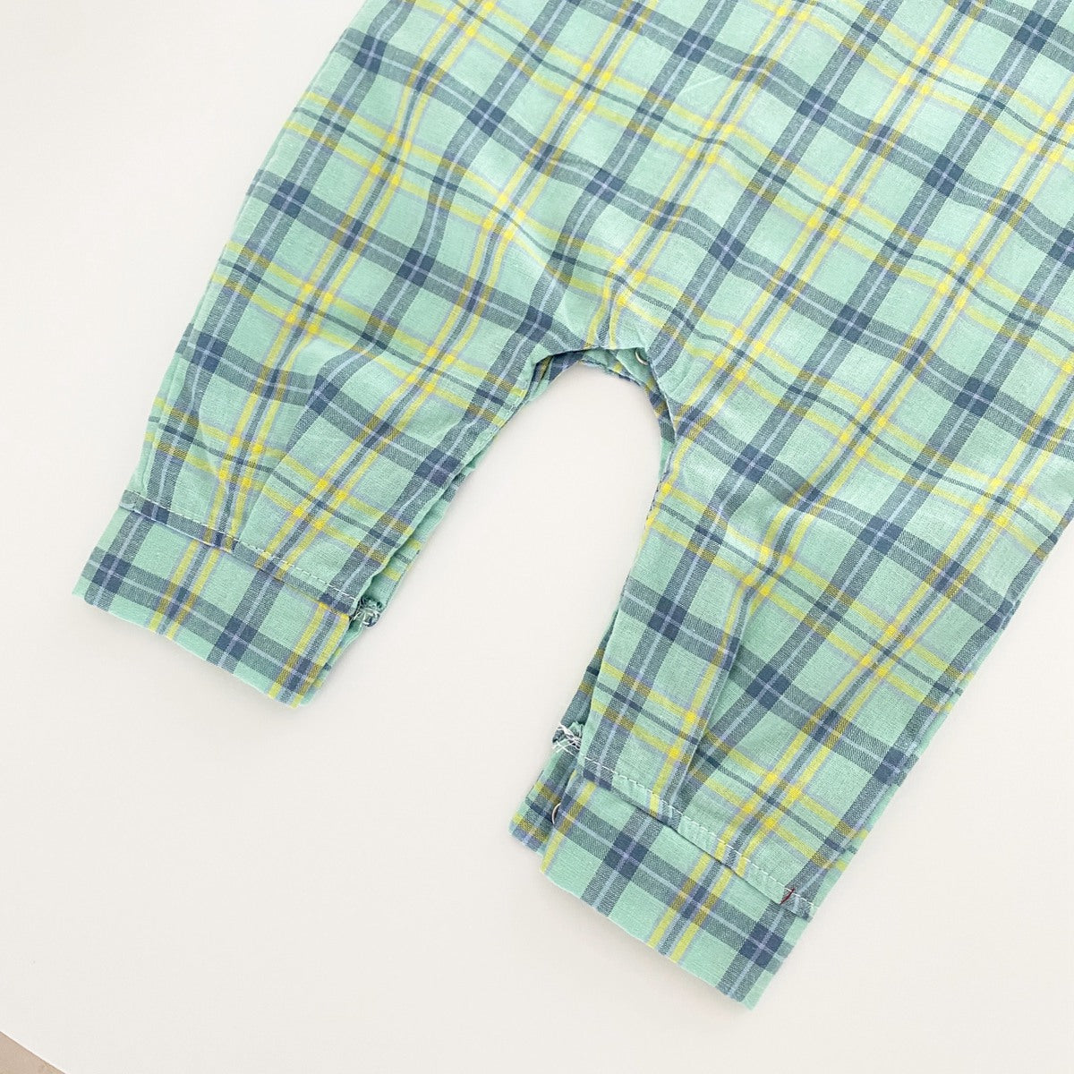 Baby boy wearing a classic plaid pattern long sleeve romper with lapel design in green and apricot colors.