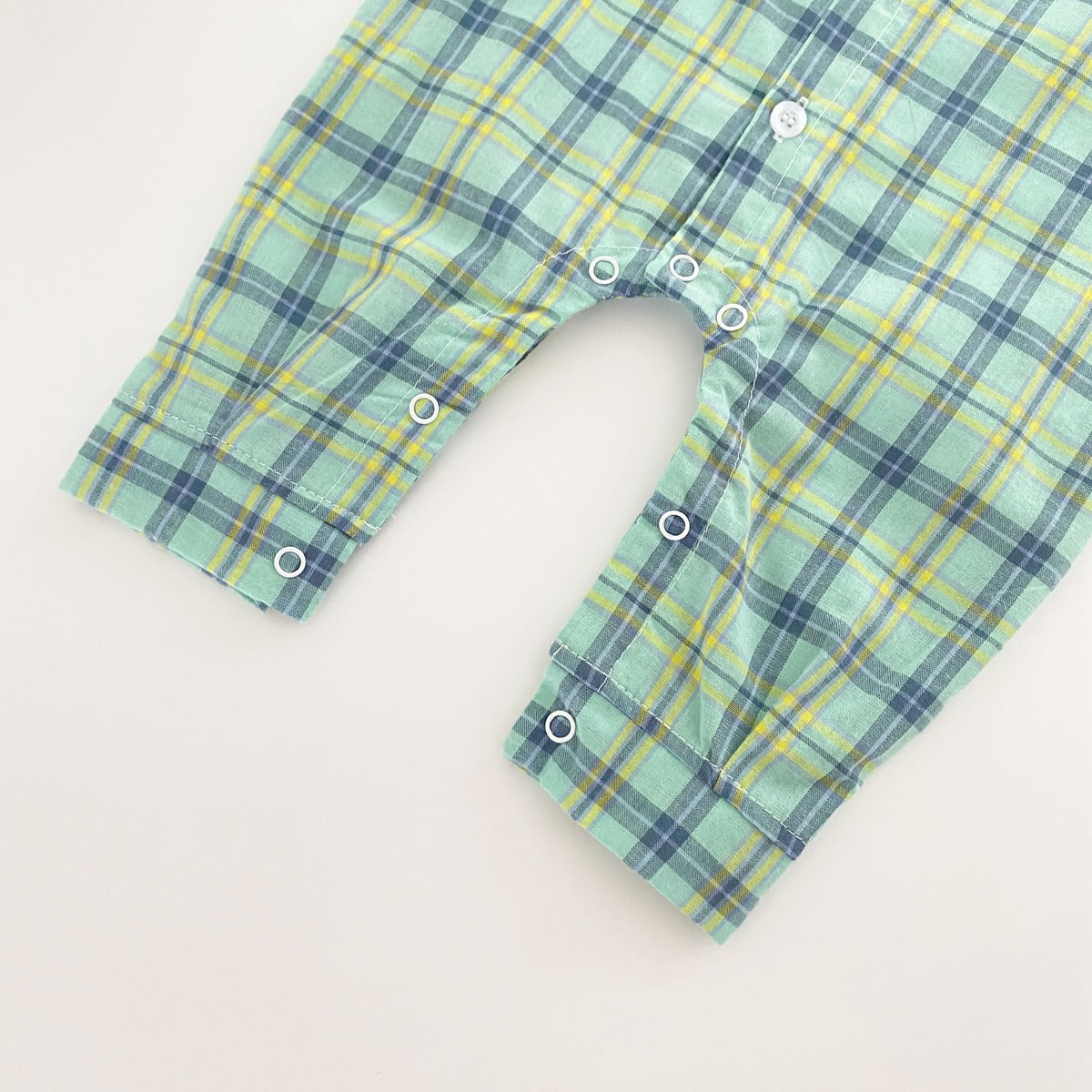 Baby boy wearing a classic plaid pattern long sleeve romper with lapel design in green and apricot colors.