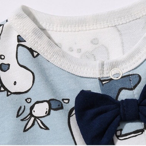 Baby boy wearing a dinosaur patterned bow tie romper with snap button closure, featuring a fun patched design.