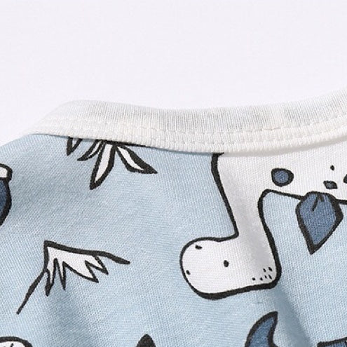 Baby boy wearing a dinosaur patterned bow tie romper with snap button closure, featuring a fun patched design.