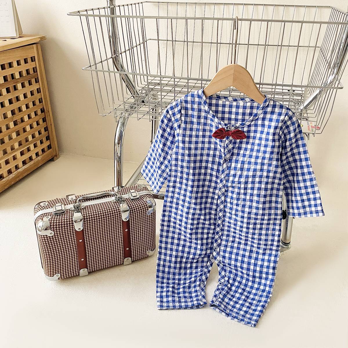 Baby boy wearing a plaid pattern cotton jumpsuit with a bow patch, showcasing comfort and style.