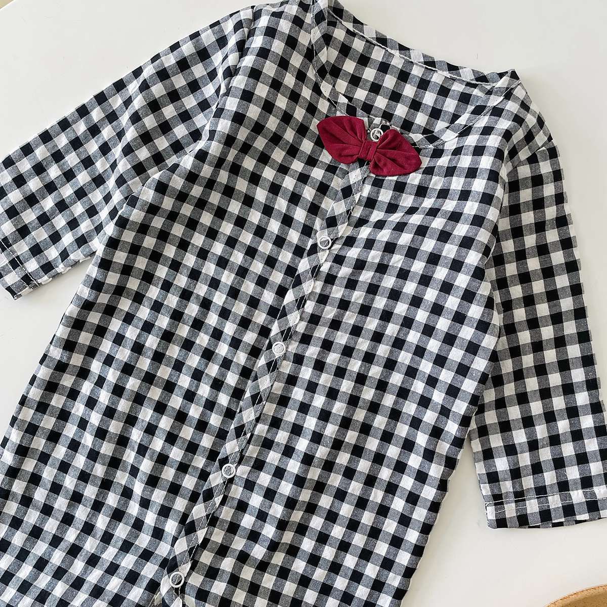 Baby boy wearing a plaid pattern cotton jumpsuit with a bow patch, showcasing comfort and style.