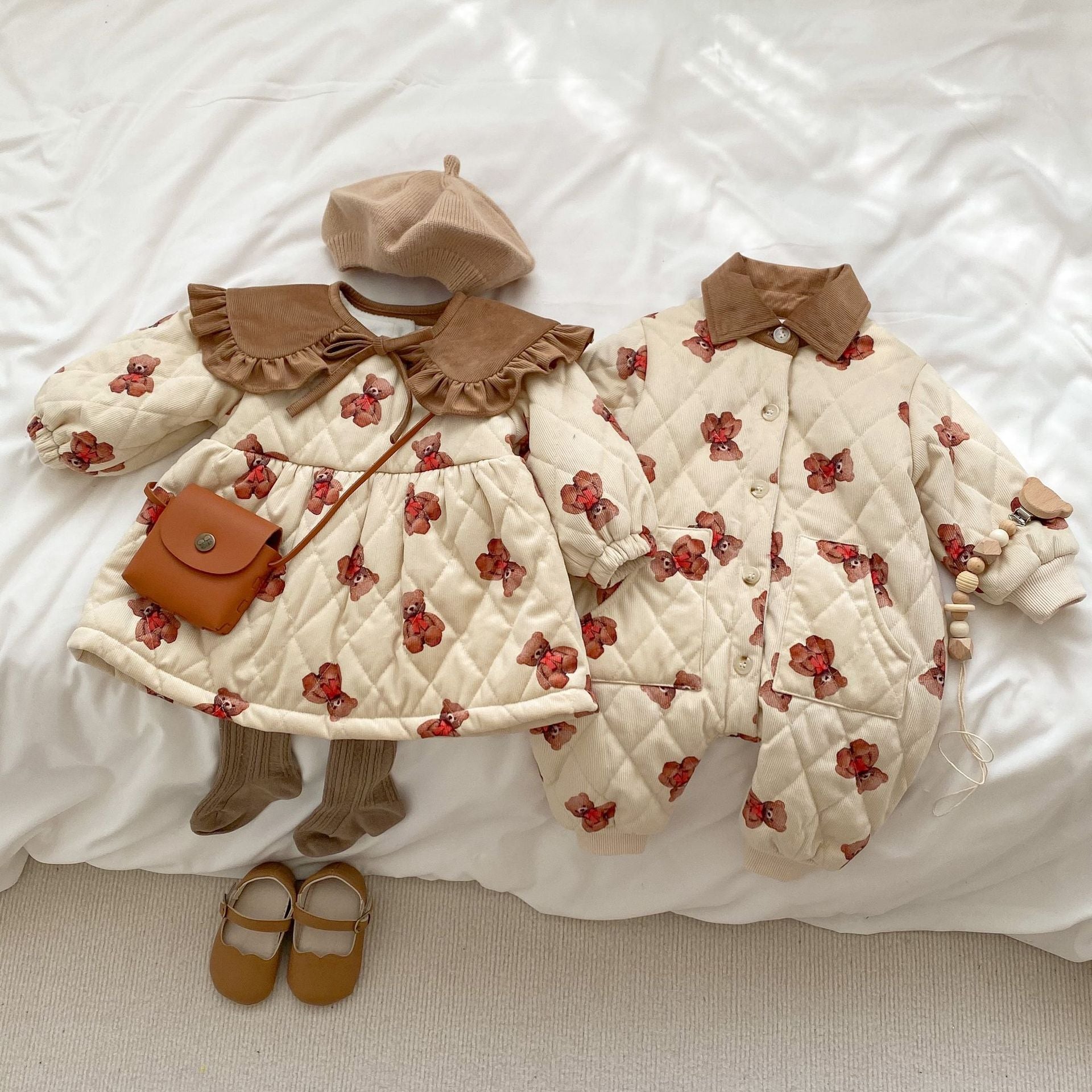 A cozy quilted baby dress featuring a cute cartoon bear graphic, available in brown and coffee colors.