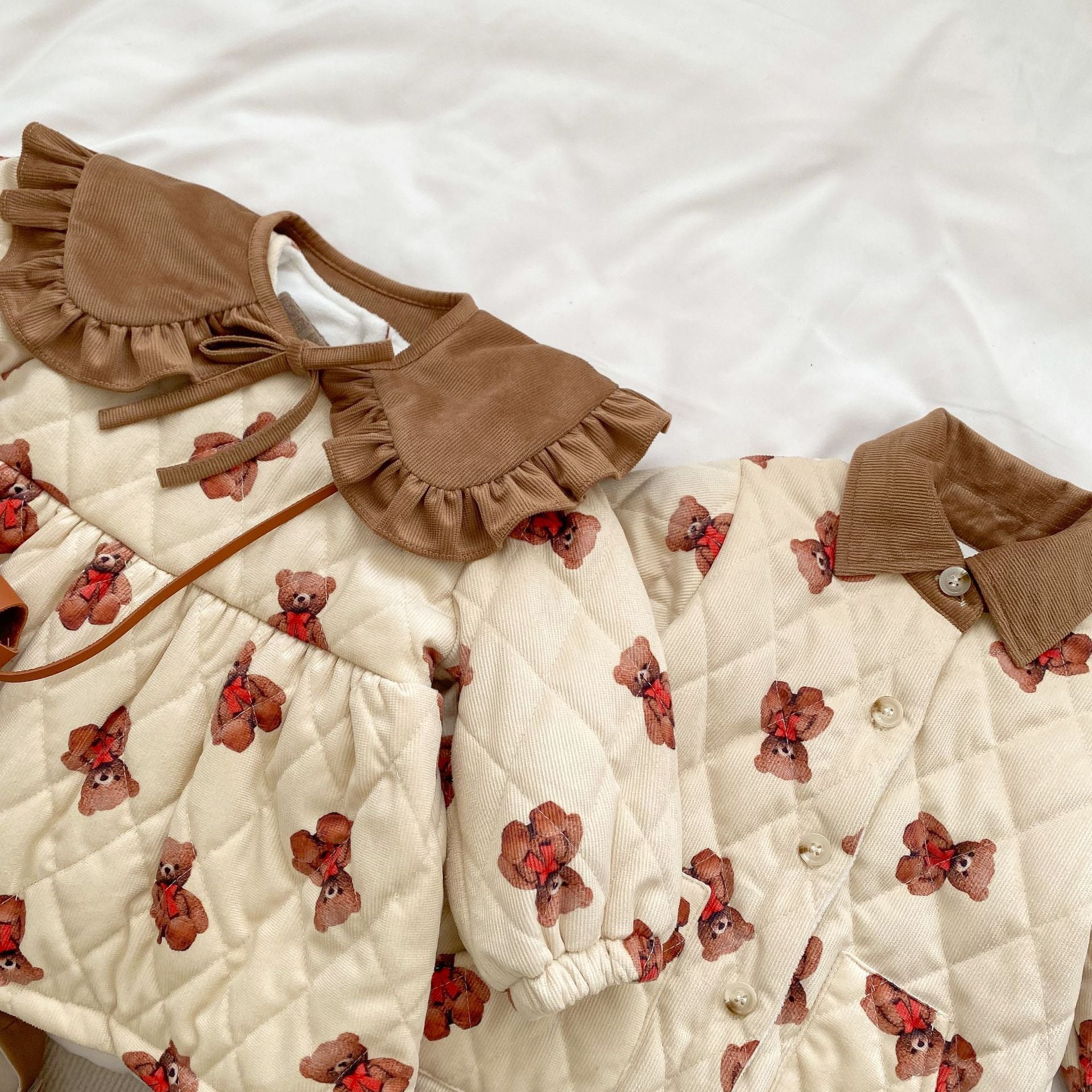 A cozy quilted baby dress featuring a cute cartoon bear graphic, available in brown and coffee colors.