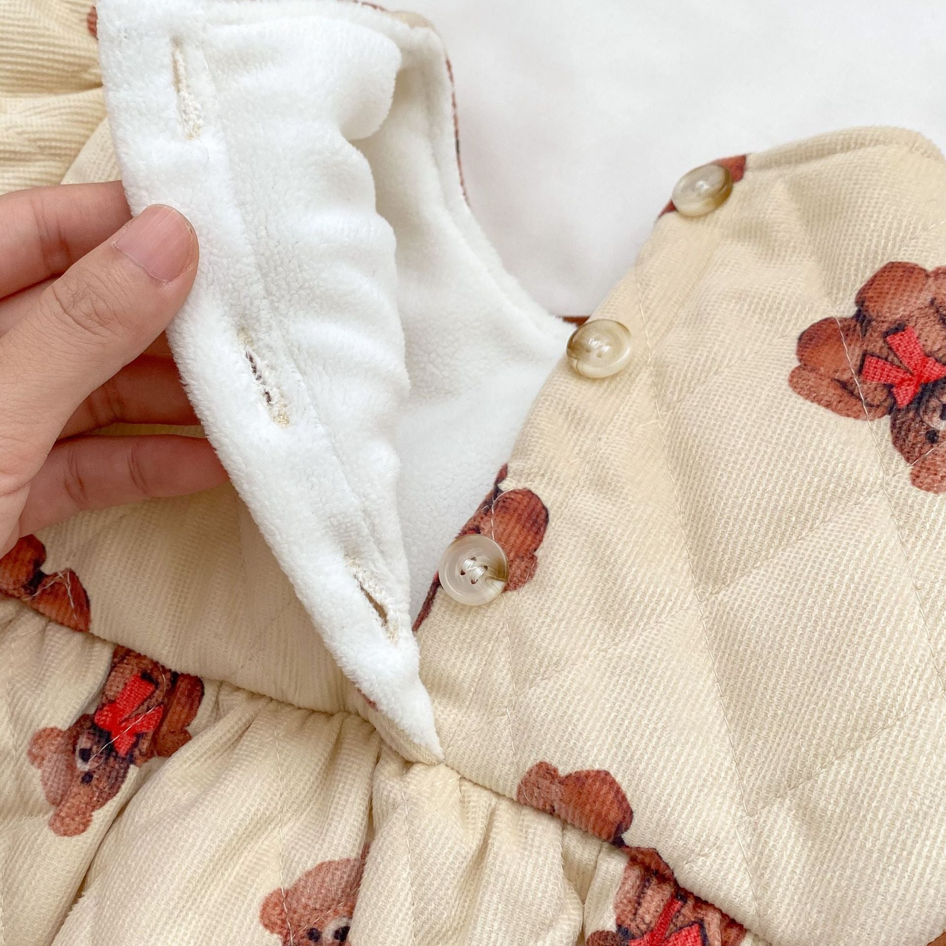 A cozy quilted baby dress featuring a cute cartoon bear graphic, available in brown and coffee colors.