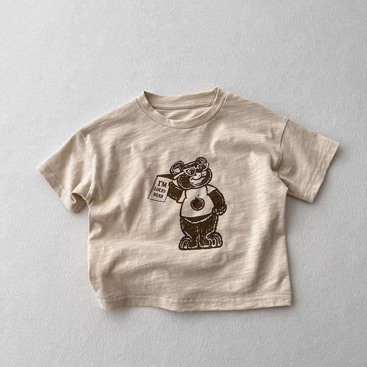 A soft apricot baby t-shirt featuring a playful cartoon bear graphic, perfect for infants and toddlers.