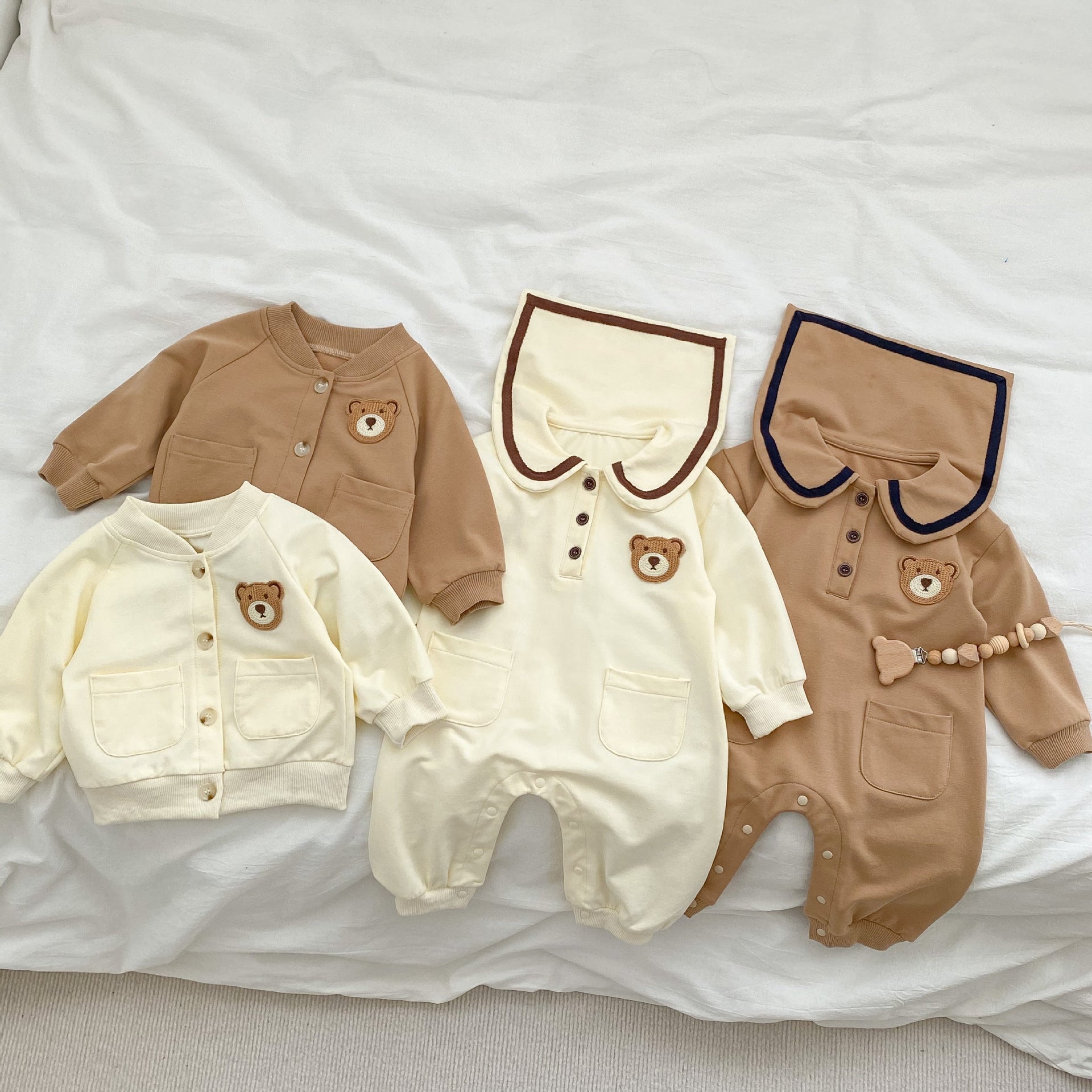 A cute baby wearing a cartoon bear patched romper and coat set in beige, showcasing its adorable design and premium cotton material.