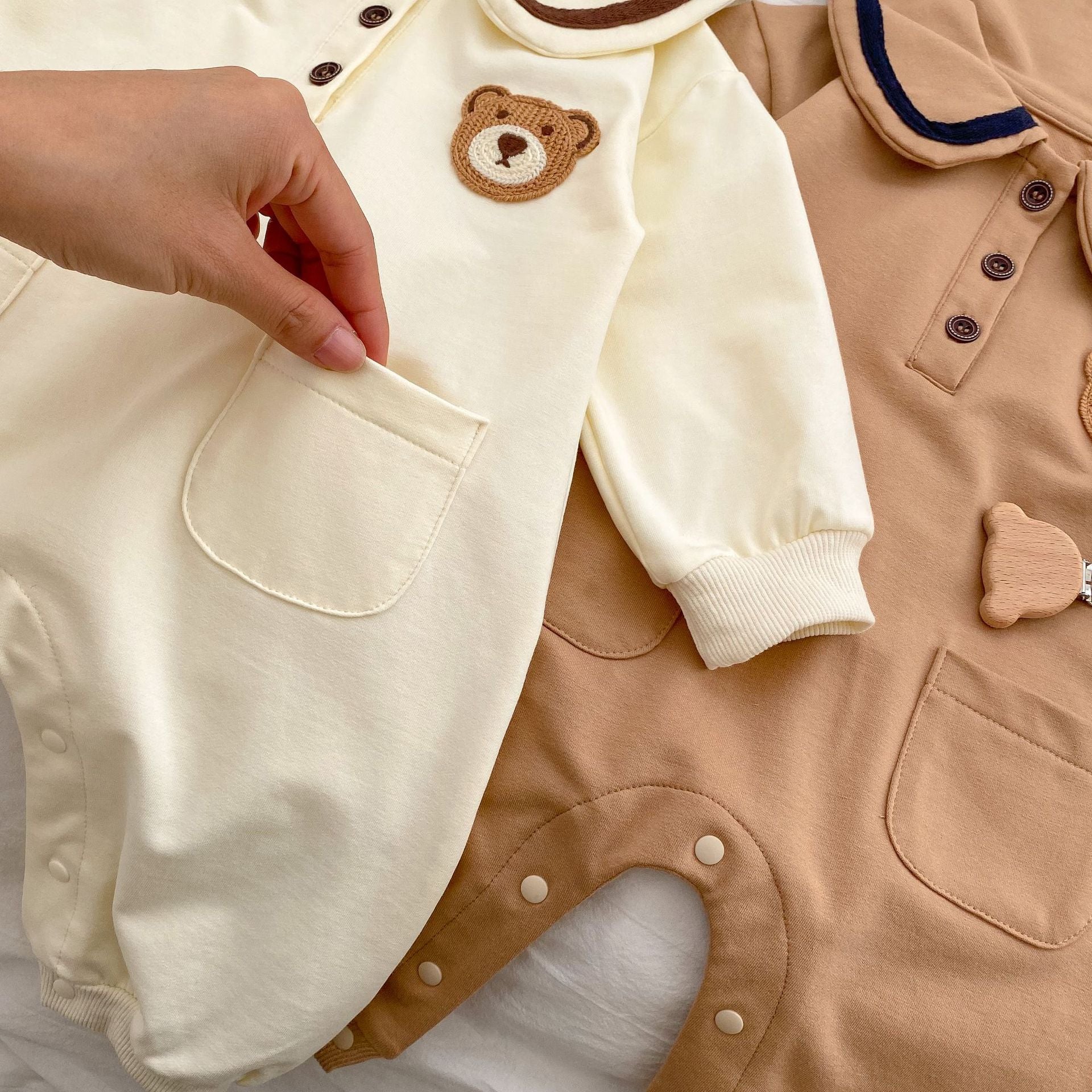 A cute baby wearing a cartoon bear patched romper and coat set in beige, showcasing its adorable design and premium cotton material.