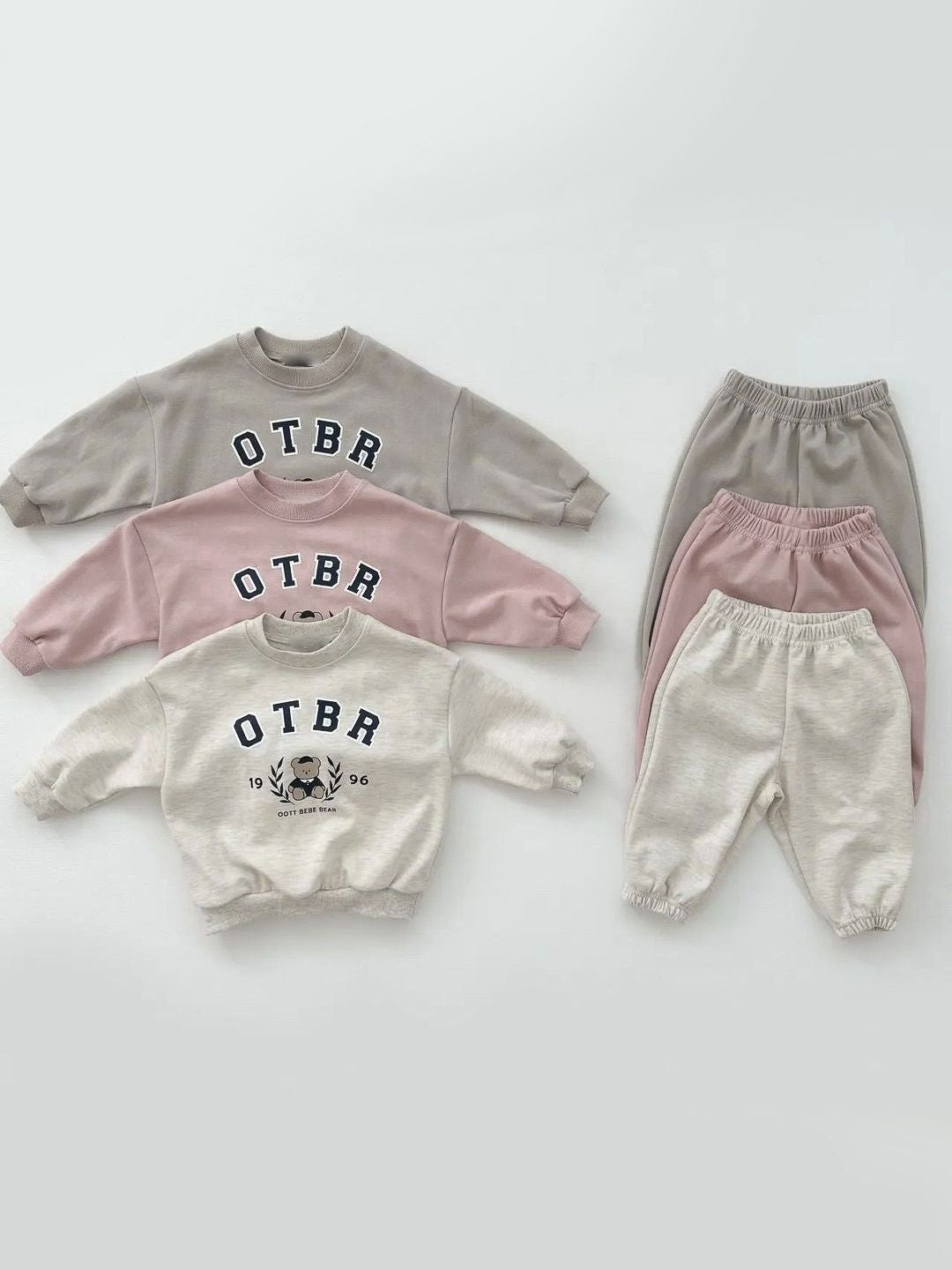 A set of baby cartoon hoodies with pants in pink and apricot colors, featuring playful designs suitable for both boys and girls.