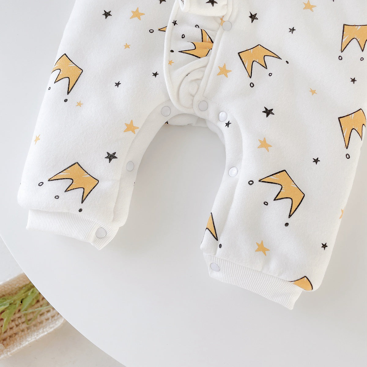 Baby girl wearing a white cartoon pattern romper with ruffles and button front closure, made from thickened fleece.