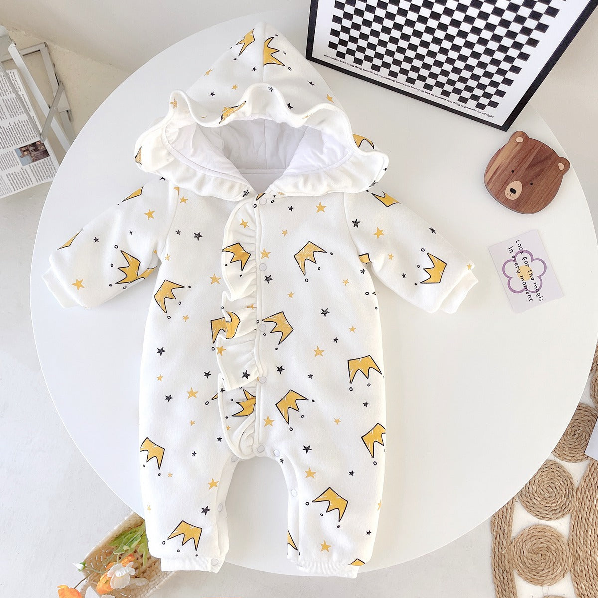 Baby girl wearing a white cartoon pattern romper with ruffles and button front closure, made from thickened fleece.