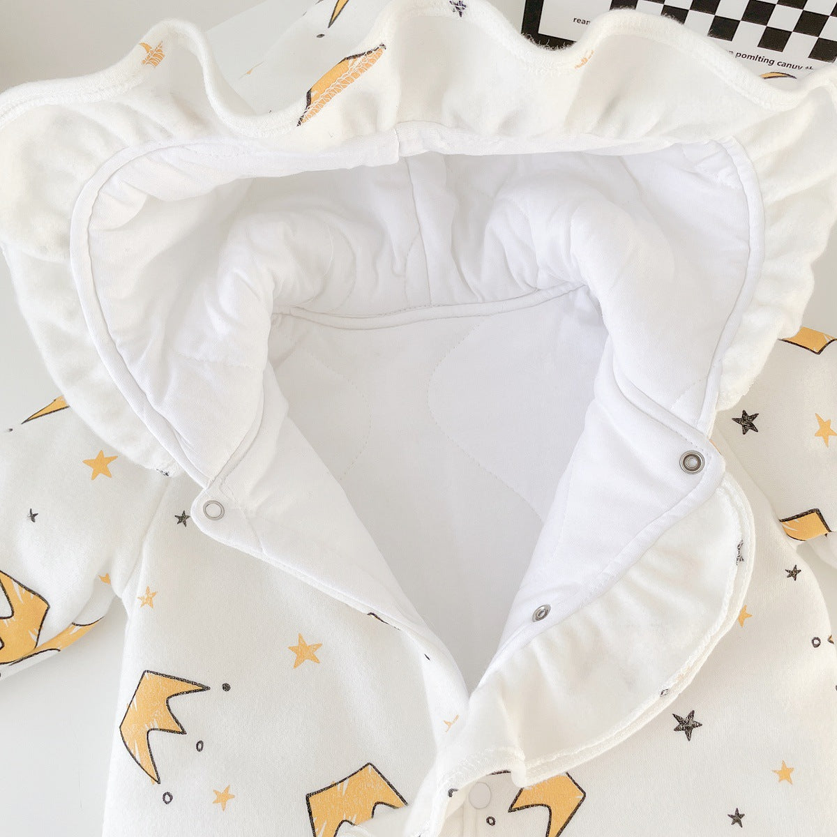 Baby girl wearing a white cartoon pattern romper with ruffles and button front closure, made from thickened fleece.