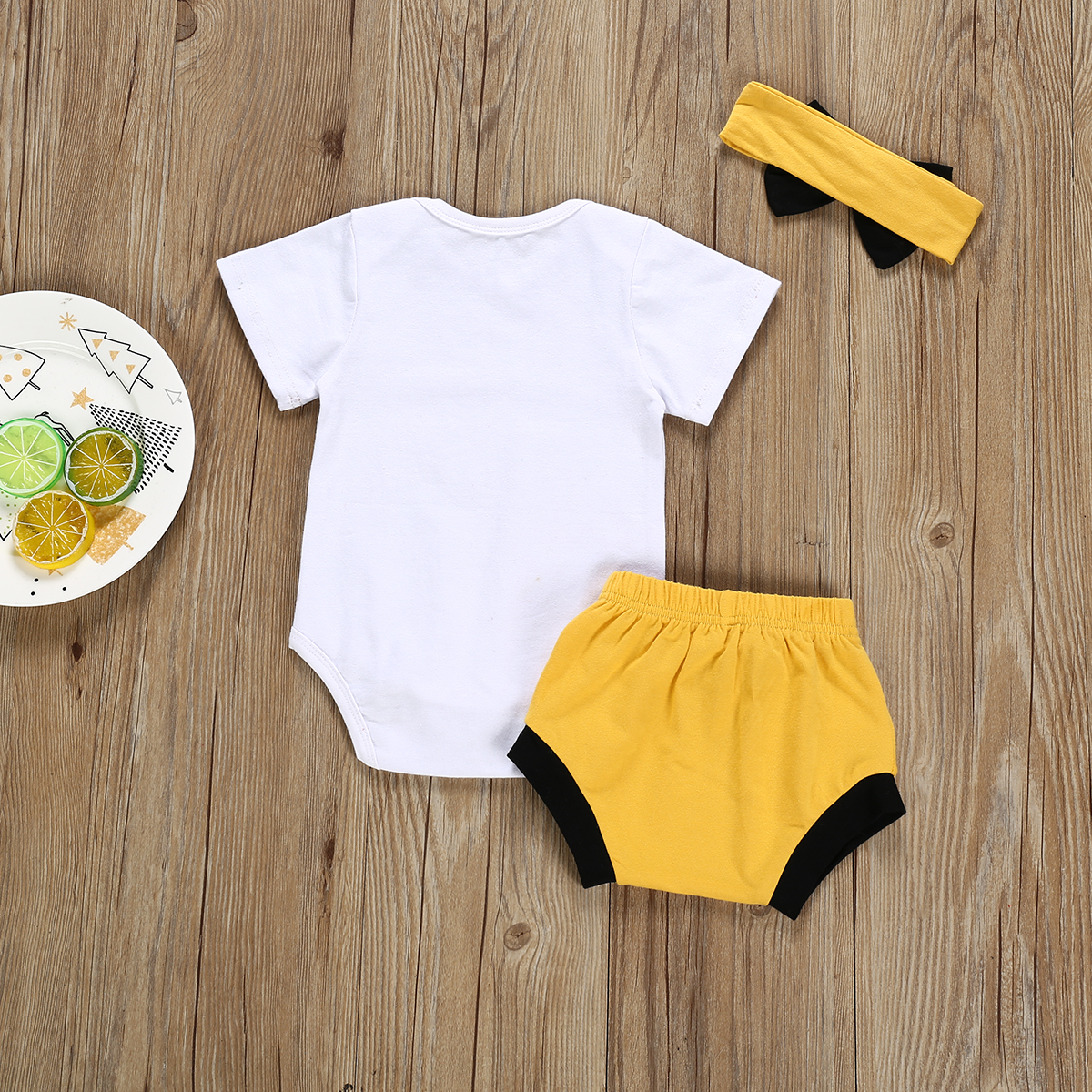 Baby outfit with headband and fruit plate.