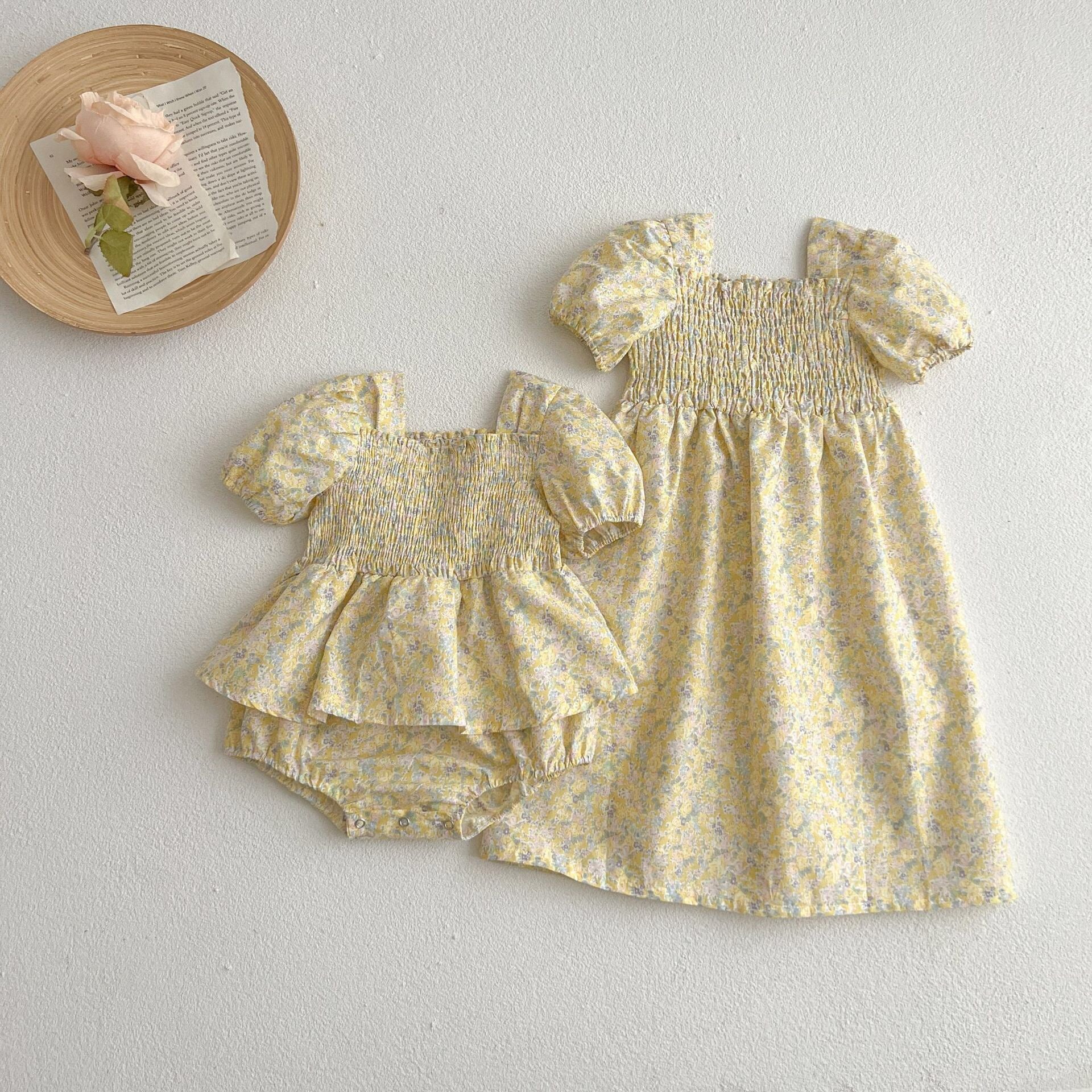 A cute baby girl wearing a yellow floral puff sleeve dress, perfect for summer outings.