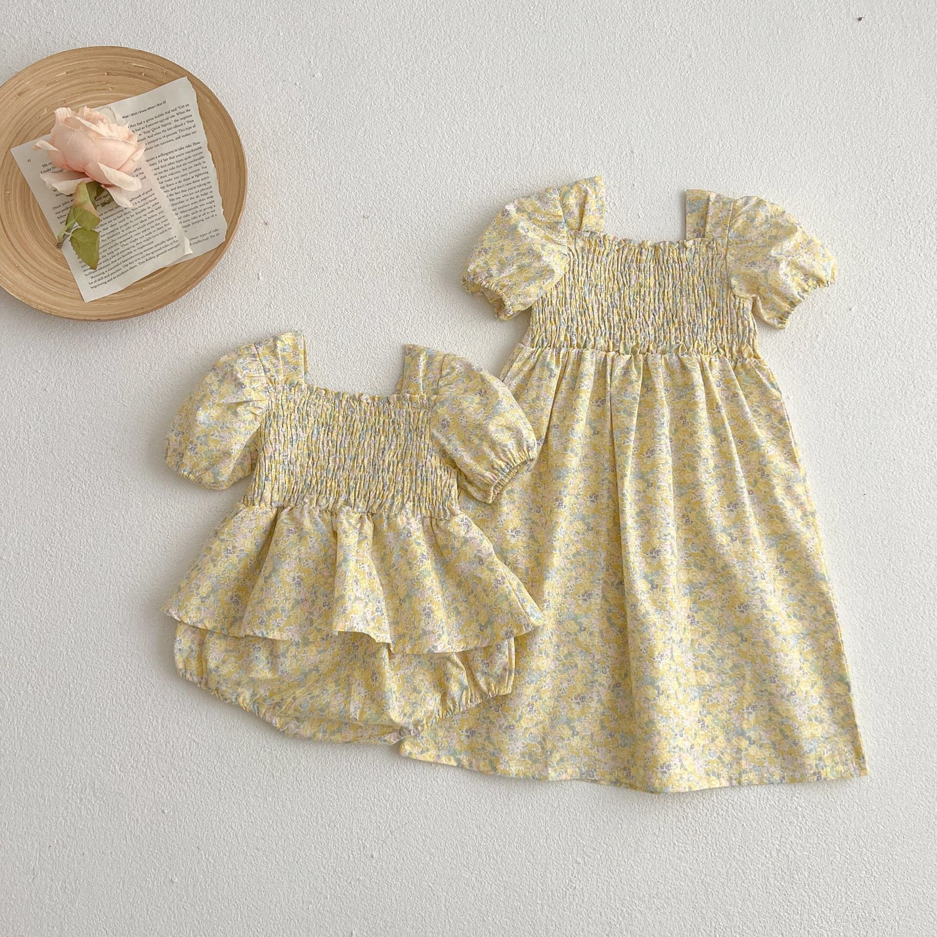 A cute baby girl wearing a yellow floral puff sleeve dress, perfect for summer outings.