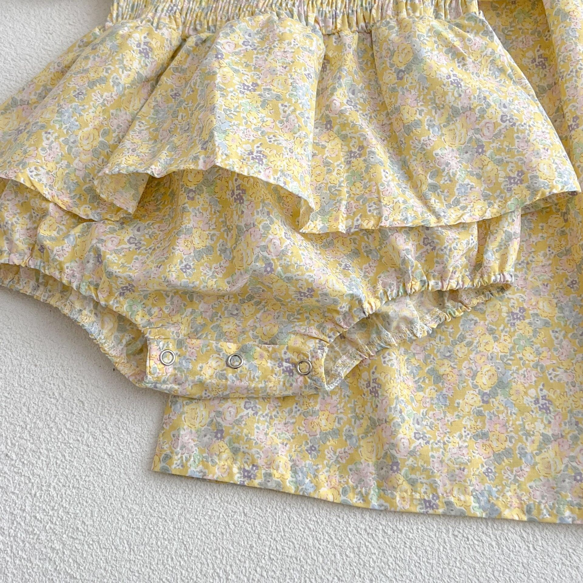 A cute baby girl wearing a yellow floral puff sleeve dress, perfect for summer outings.