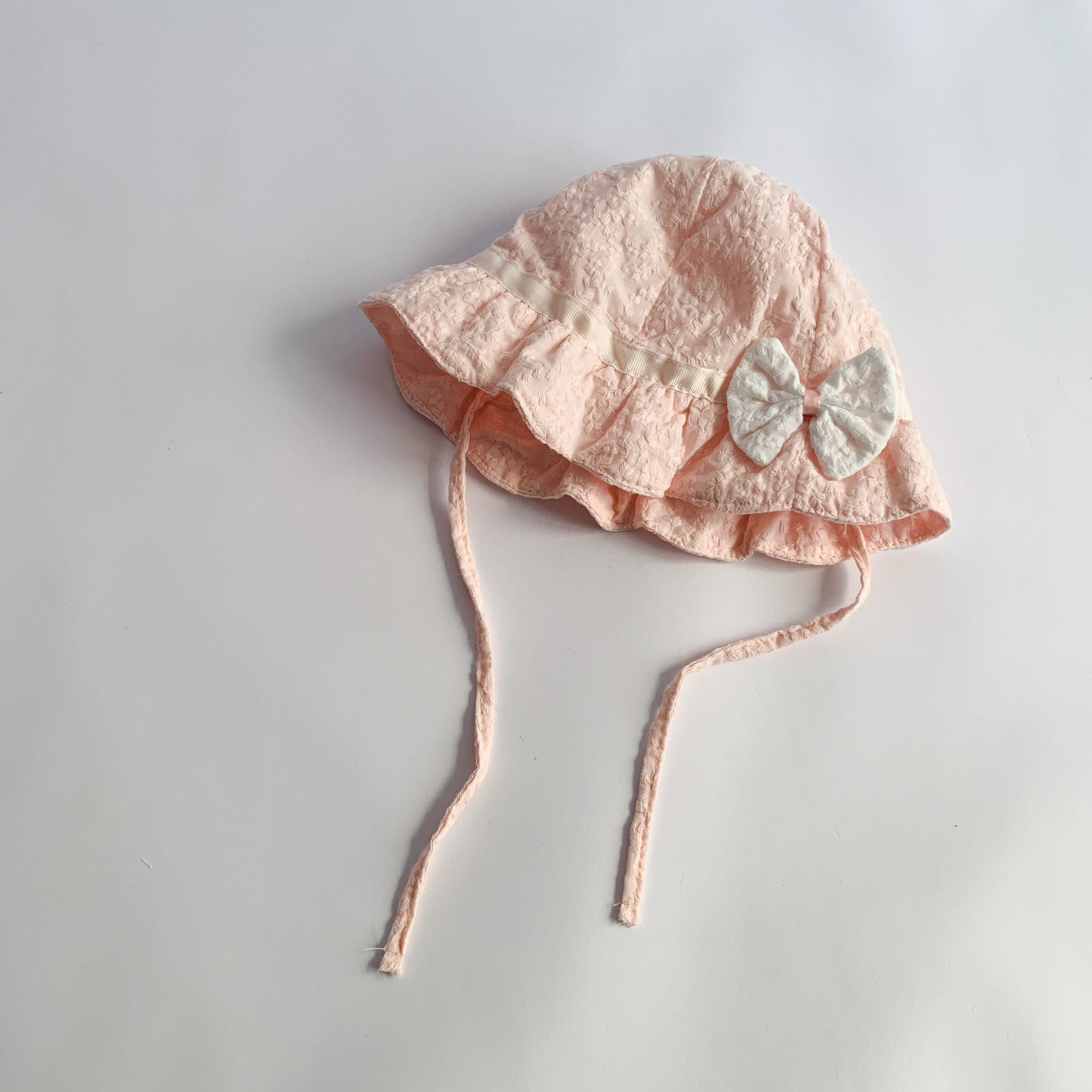 Baby sunshade hat in solid color with embroidered patterns and a bow decoration, perfect for stylish baby girls.