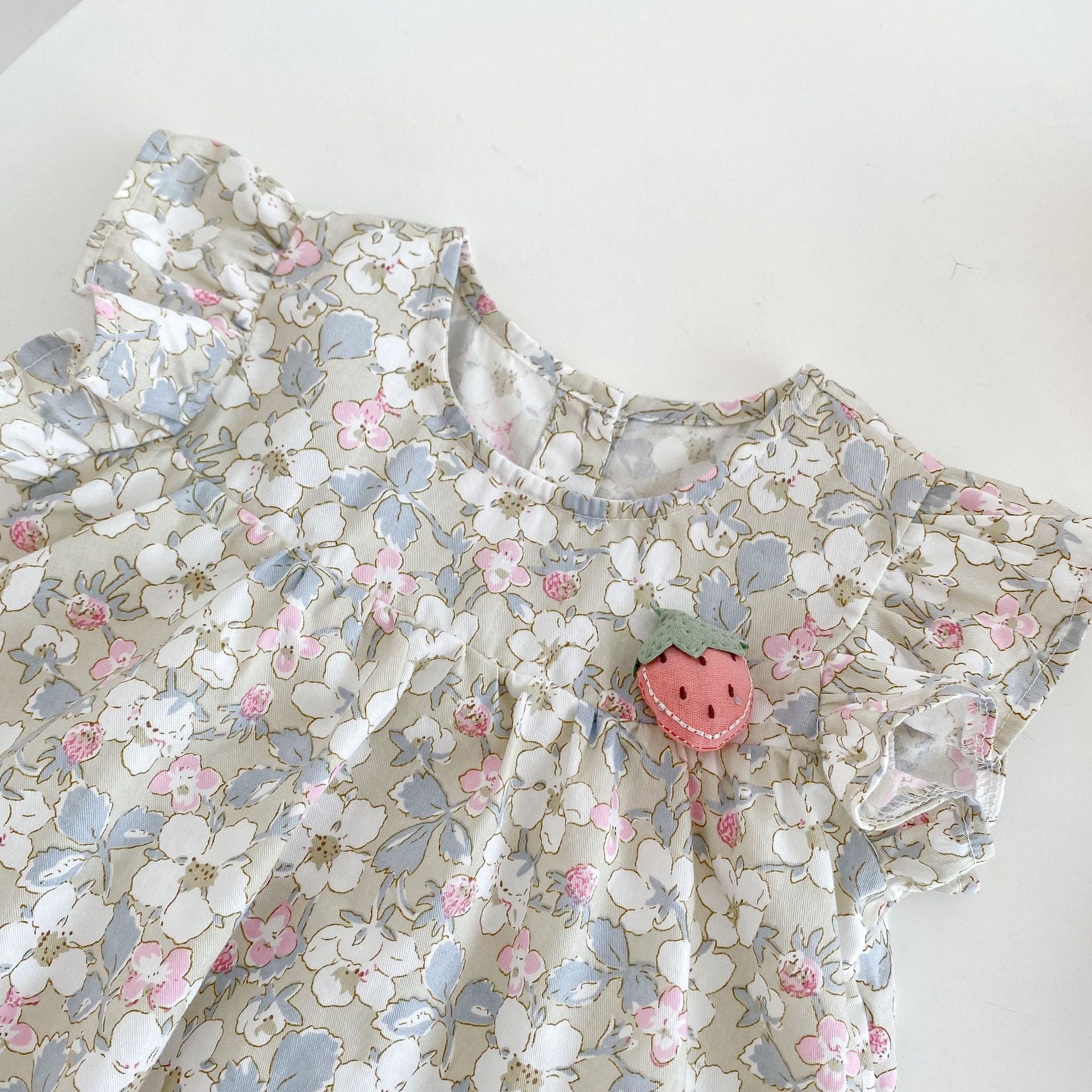 A vibrant baby dress featuring a floral graphic and 3D strawberry patch design with butterfly sleeves, perfect for summer wear.