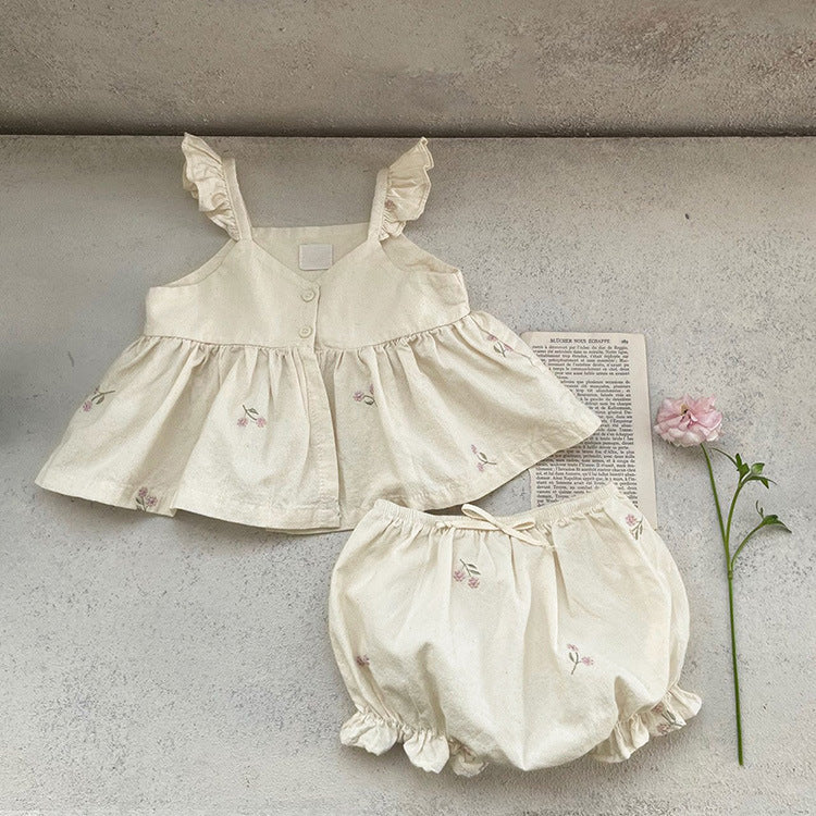 Baby girl wearing a floral embroidered ruffle sling top and shorts set in apricot color, showcasing delicate embroidery and ruffles.