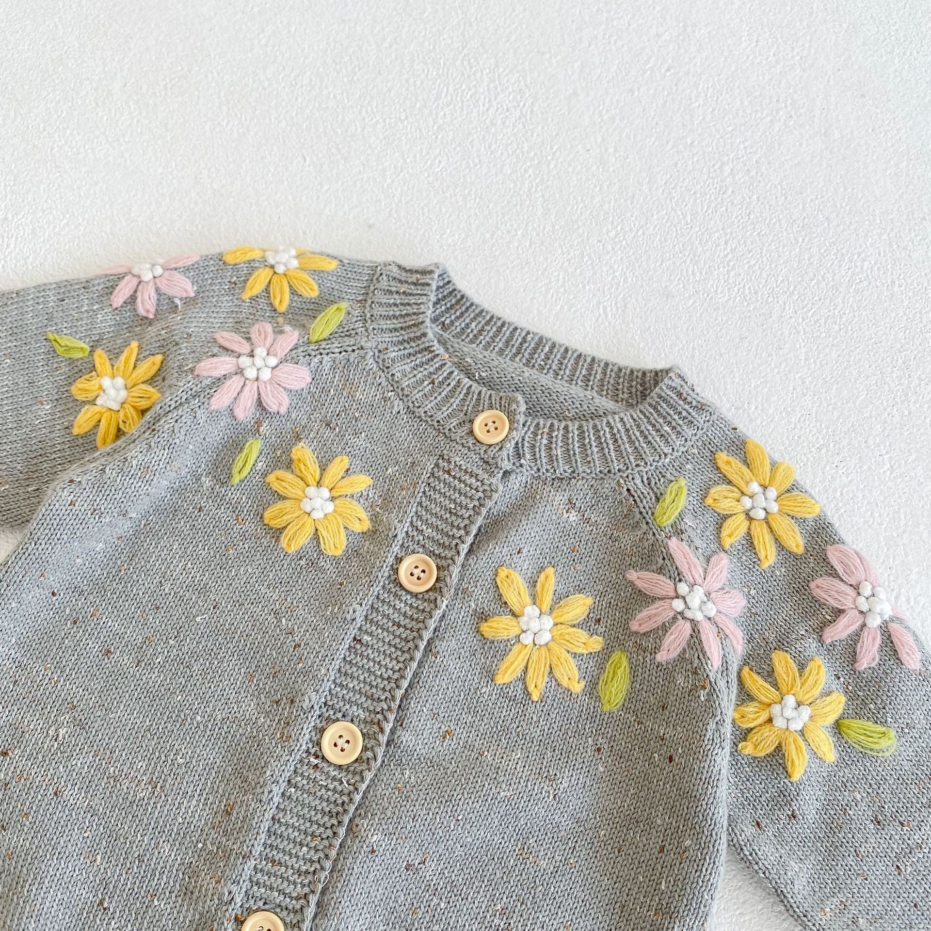 Baby girl wearing a grey floral embroidered knitted coat with single breasted closure, showcasing a stylish design for special occasions.