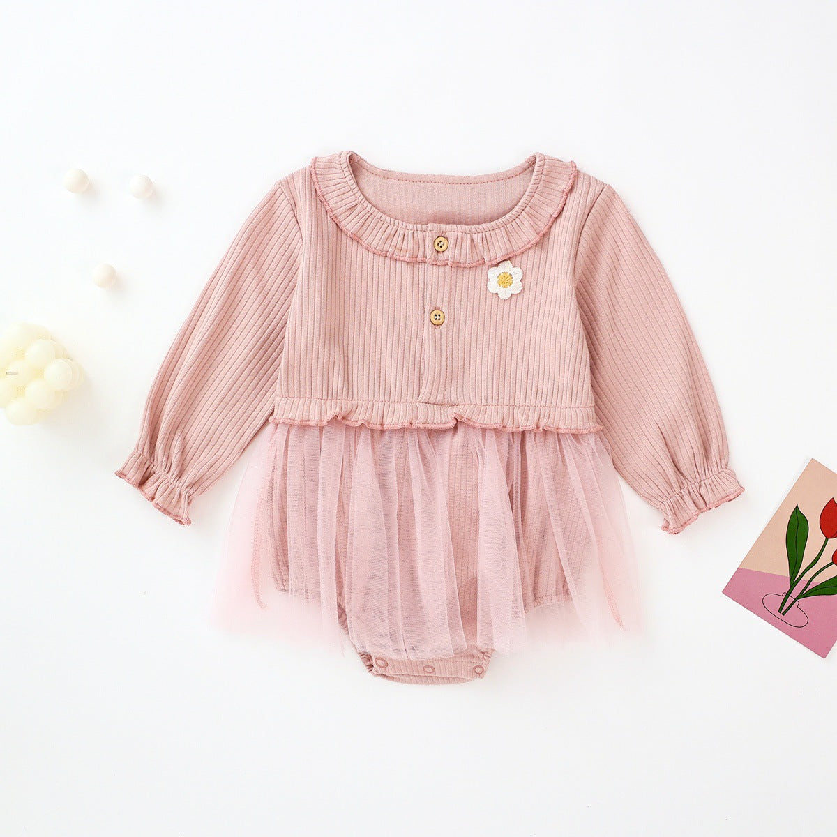 Baby girl onesie dress featuring floral patches and mesh overlay in white and pink colors.