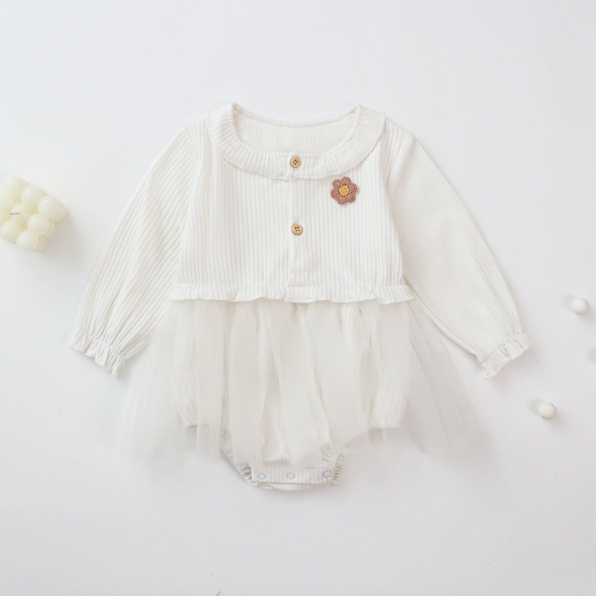 Baby girl onesie dress featuring floral patches and mesh overlay in white and pink colors.