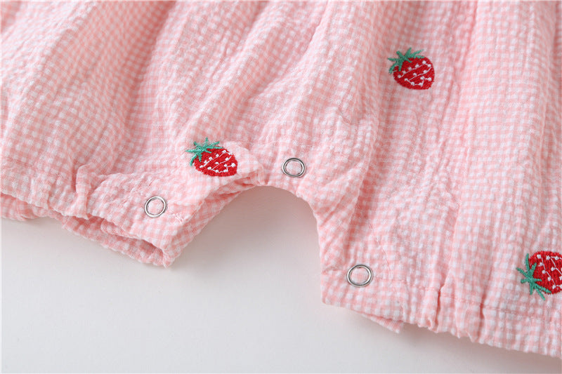 Adorable baby girl wearing a plaid jumpsuit with strawberry embroidery and snap button closure, showcasing a playful summer outfit.