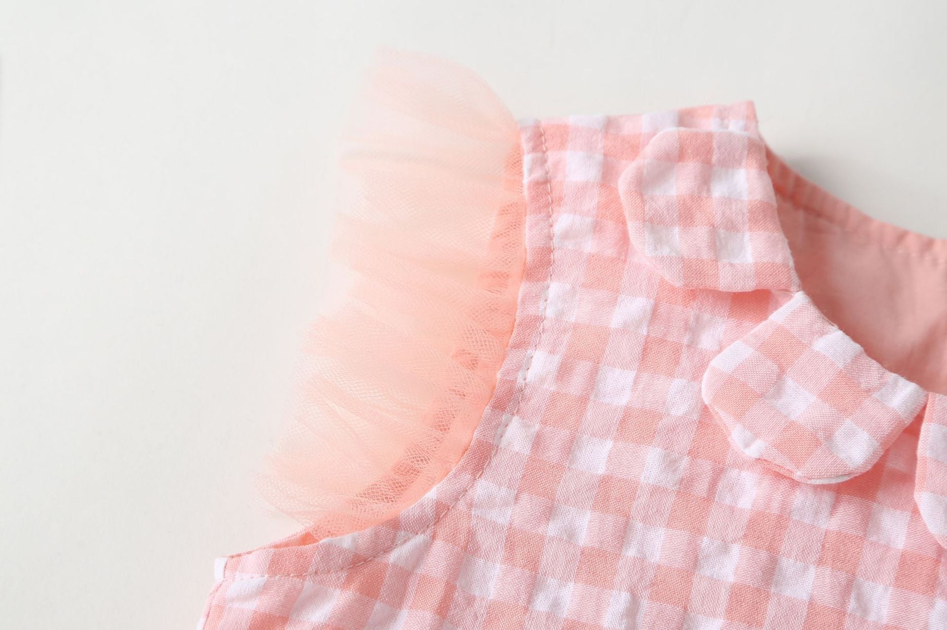 Baby girl dress featuring plaid graphic design, strawberry embroidery, and mesh overlay in pink and green colors.