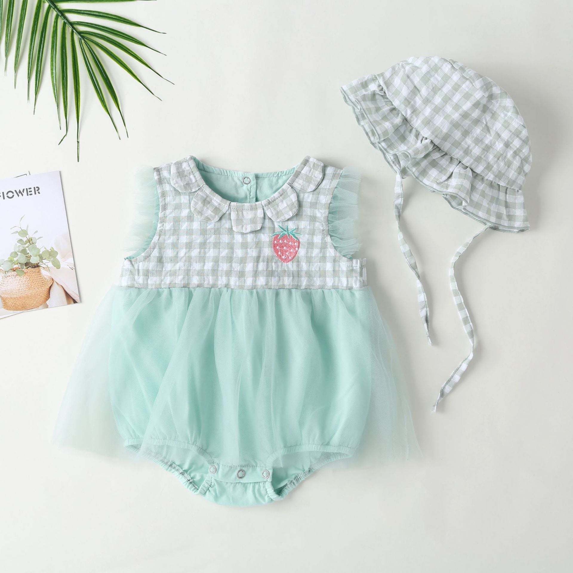 Baby girl dress featuring plaid graphic design, strawberry embroidery, and mesh overlay in pink and green colors.