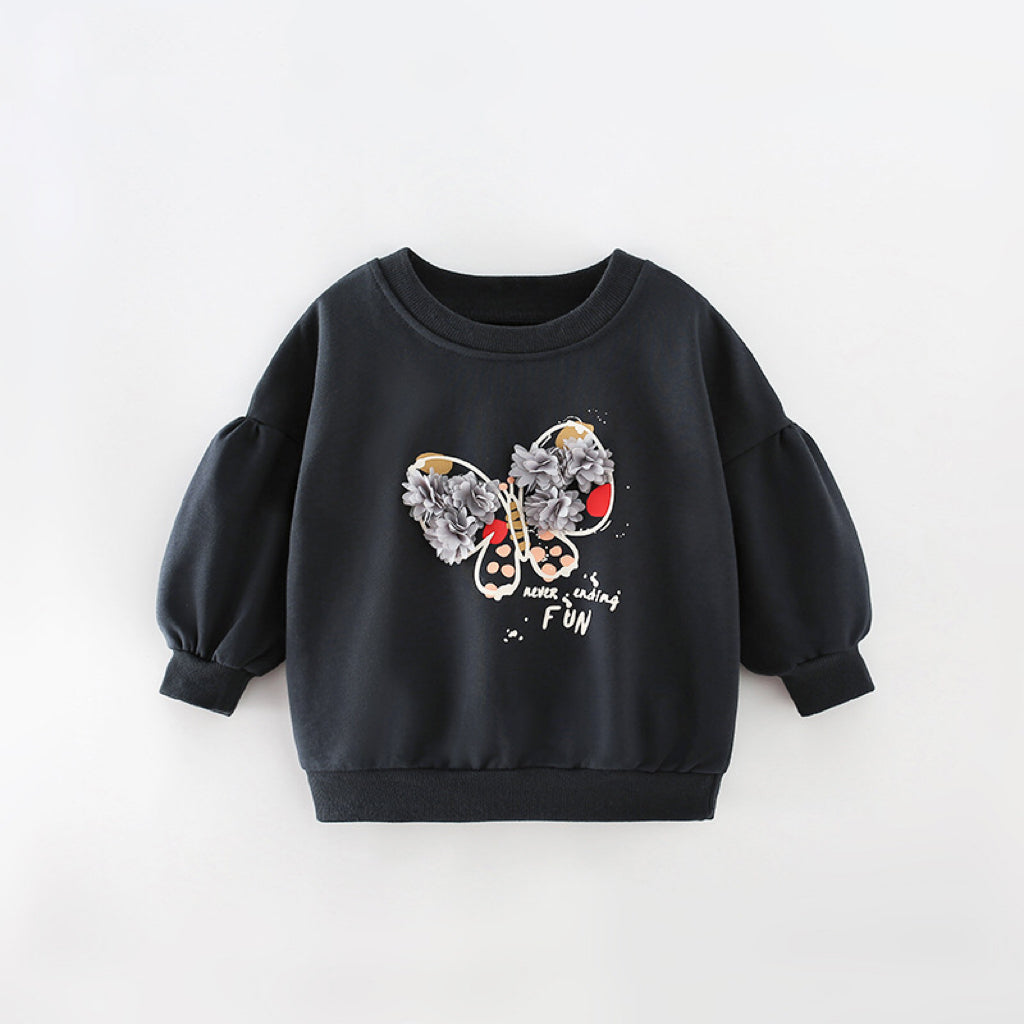 Baby girl wearing a stylish black hoodie with 3D flower patches and butterfly graphic, featuring puff sleeves.