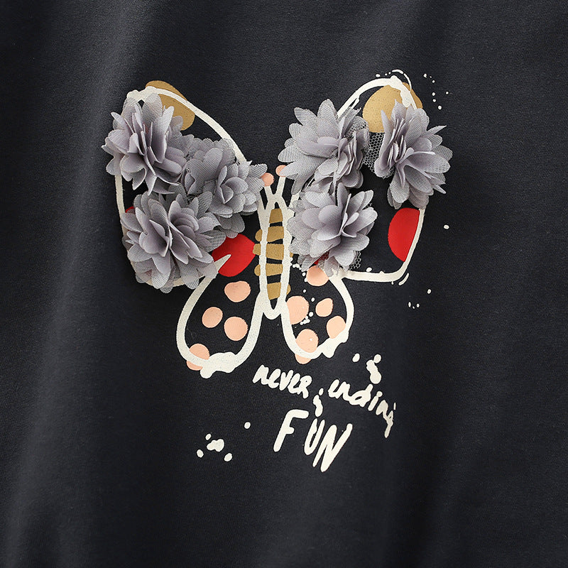 Baby girl wearing a stylish black hoodie with 3D flower patches and butterfly graphic, featuring puff sleeves.