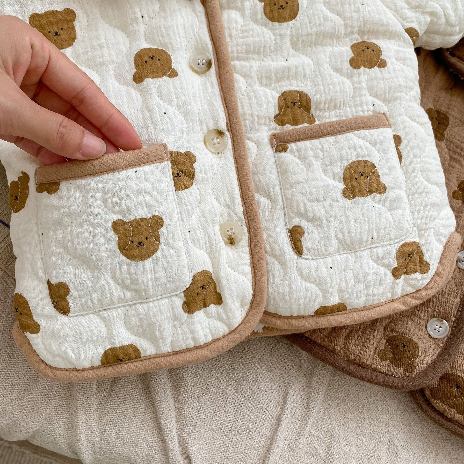 A cozy baby girl quilted cotton coat featuring an all-over bear graphic in white and brown colors, perfect for chilly weather.