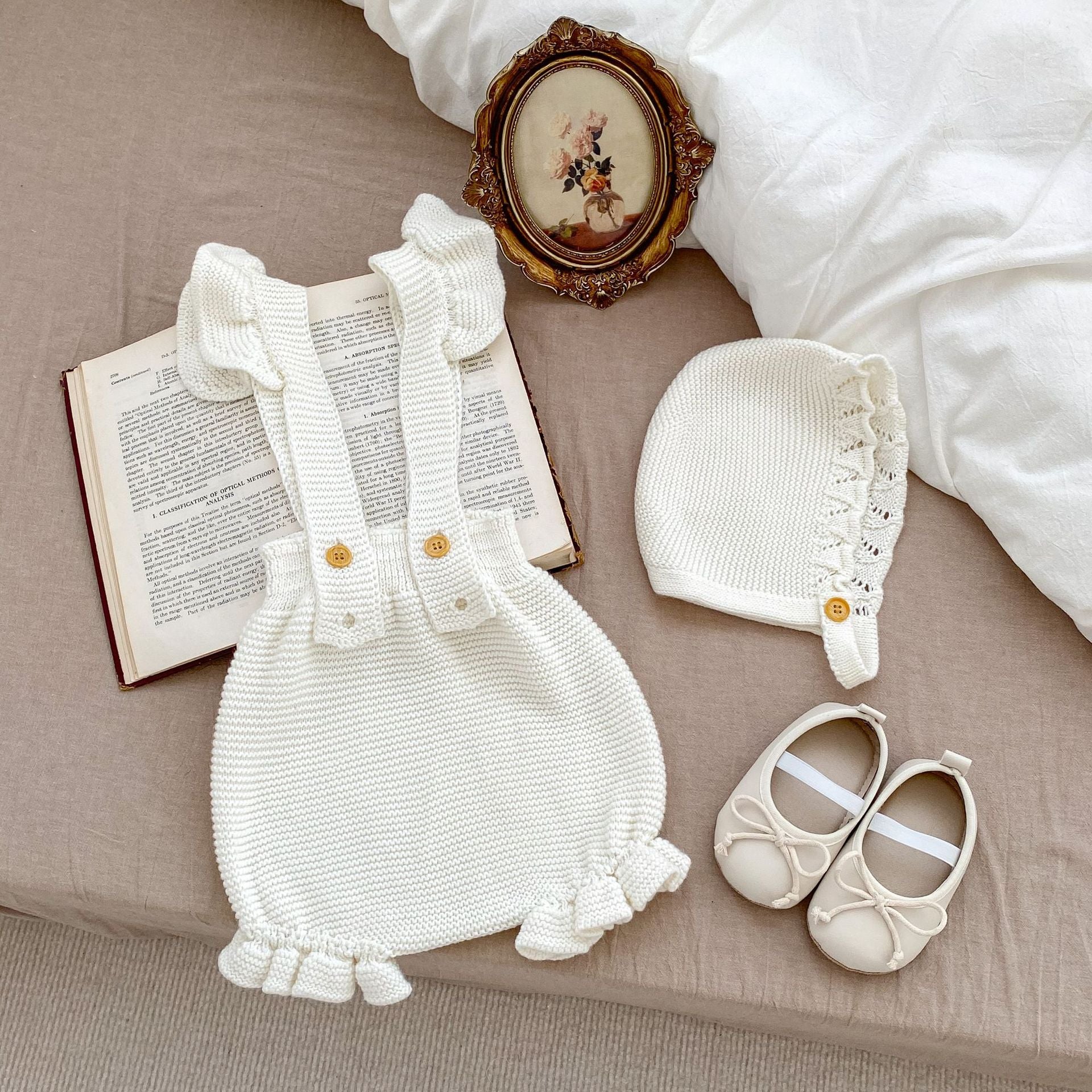 Baby girl wearing a white knitted camisole vest with a matching cap, perfect for spring and autumn.