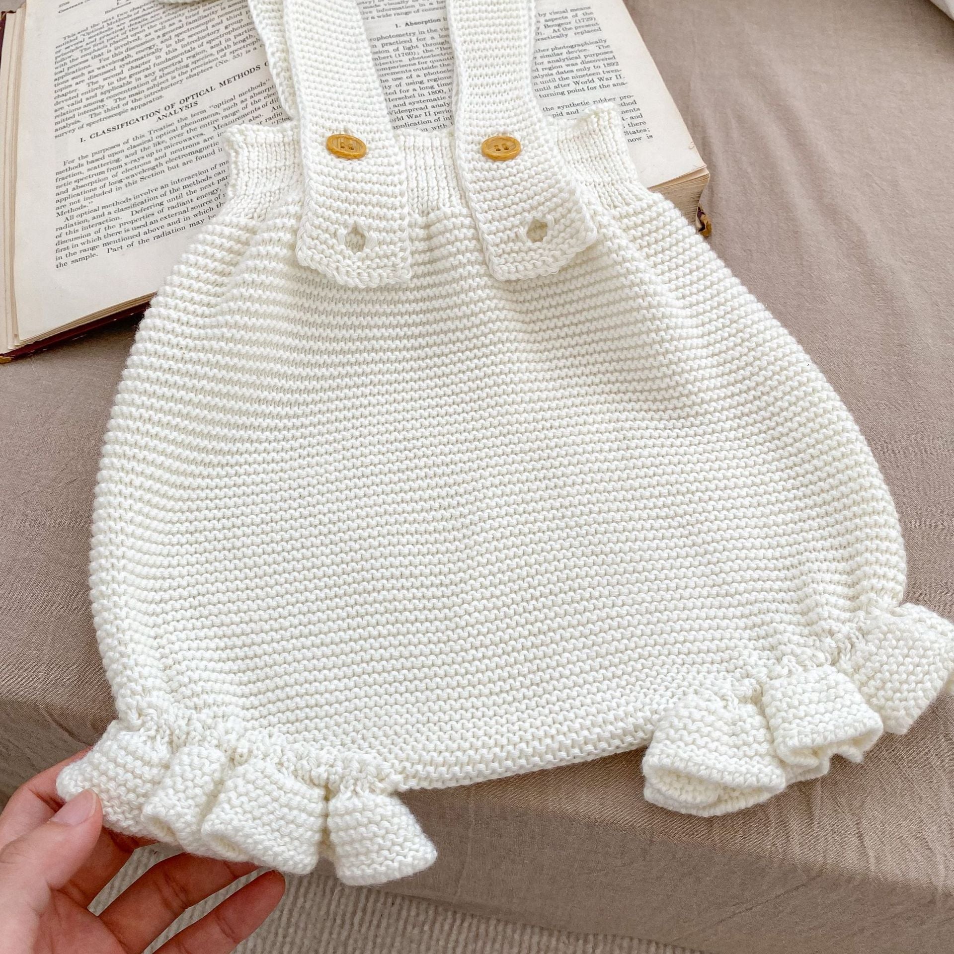 Baby girl wearing a white knitted camisole vest with a matching cap, perfect for spring and autumn.