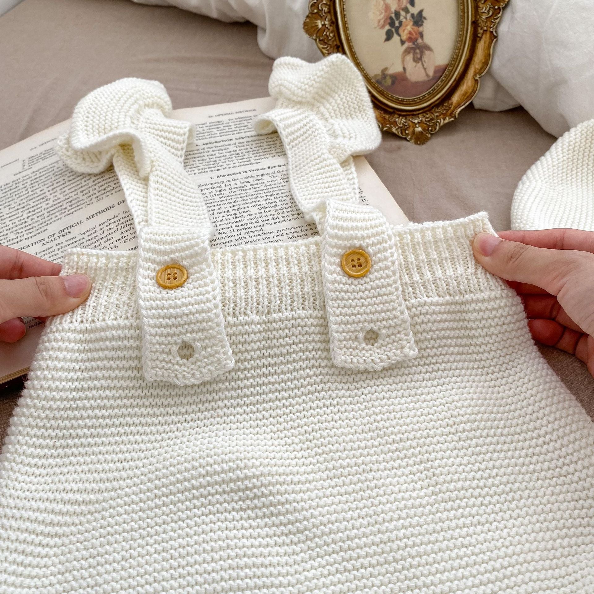 Baby girl wearing a white knitted camisole vest with a matching cap, perfect for spring and autumn.