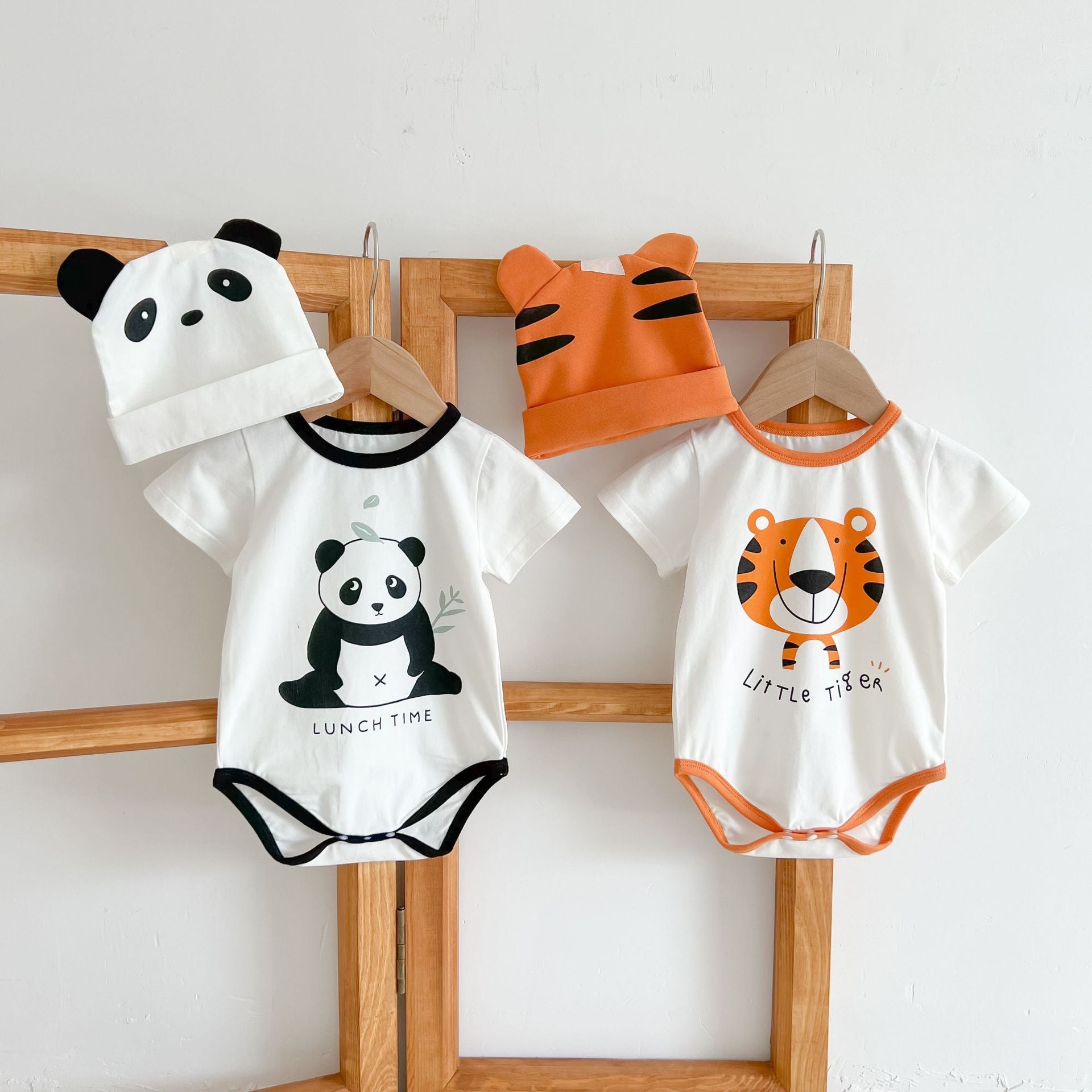 Baby girl onesie featuring a cartoon animal print with a round collar and short sleeves, available in white and orange colors.