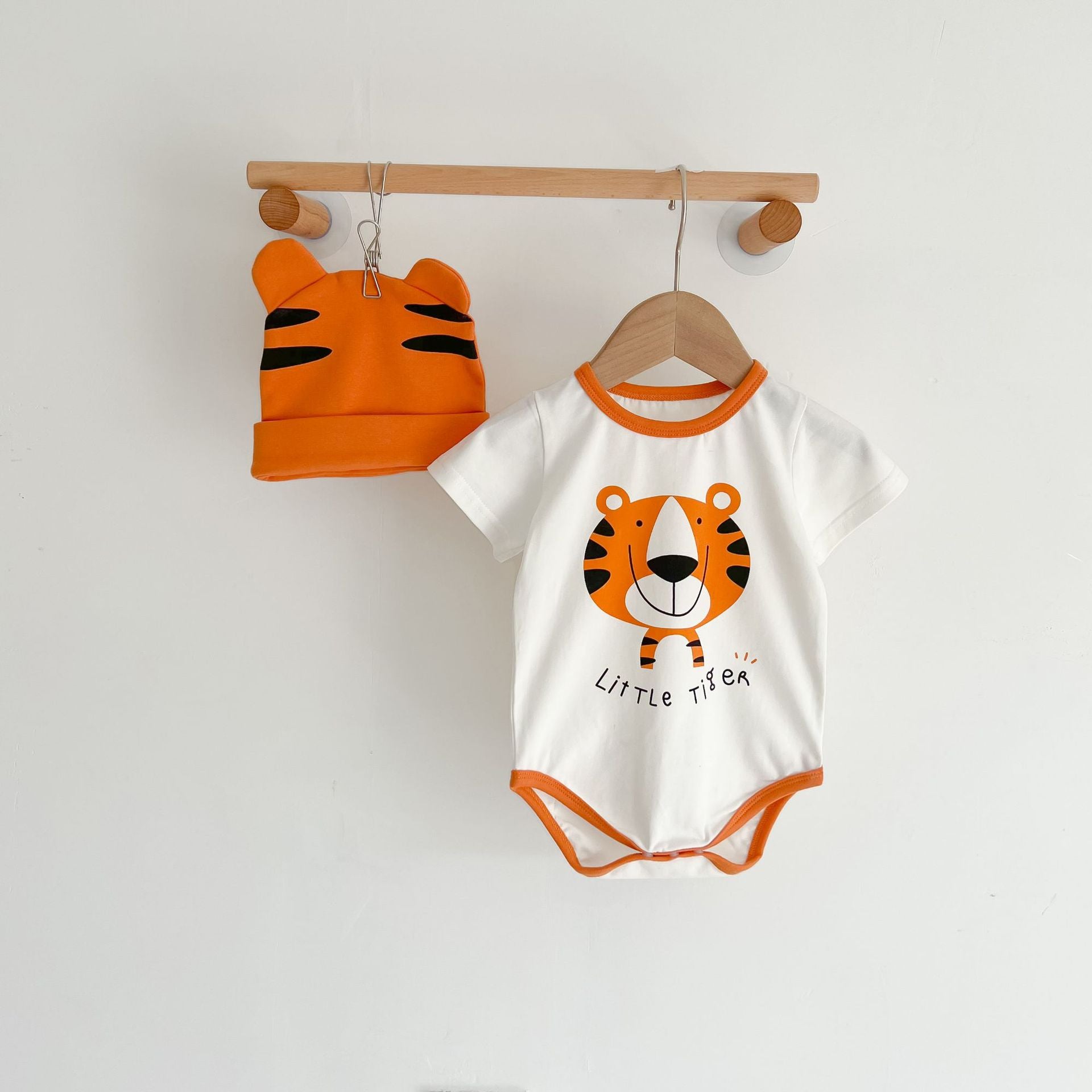 Baby girl onesie featuring a cartoon animal print with a round collar and short sleeves, available in white and orange colors.