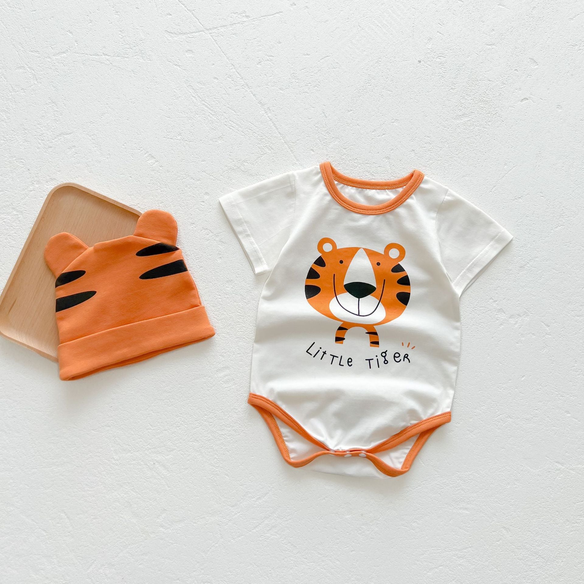 Baby girl onesie featuring a cartoon animal print with a round collar and short sleeves, available in white and orange colors.