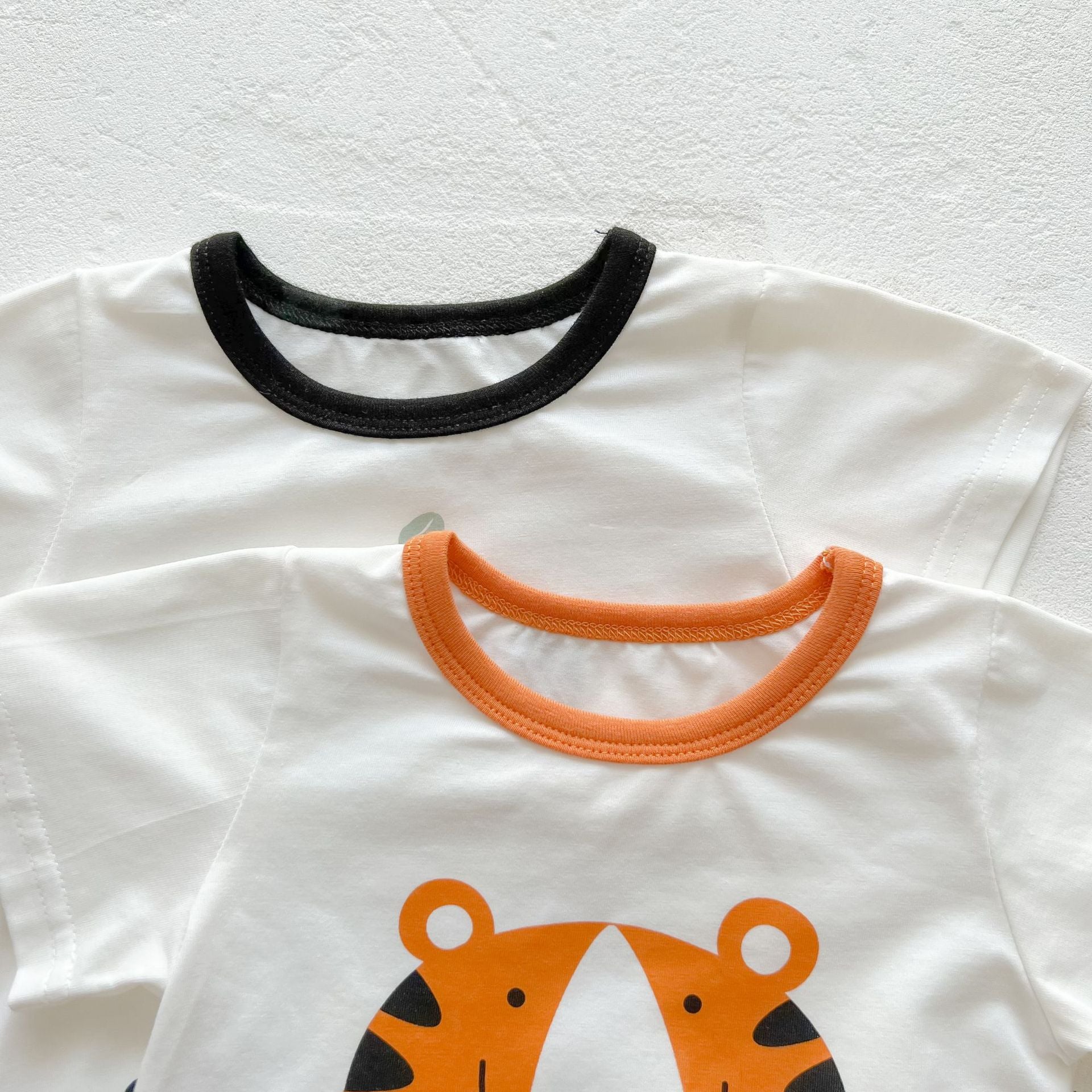 Baby girl onesie featuring a cartoon animal print with a round collar and short sleeves, available in white and orange colors.