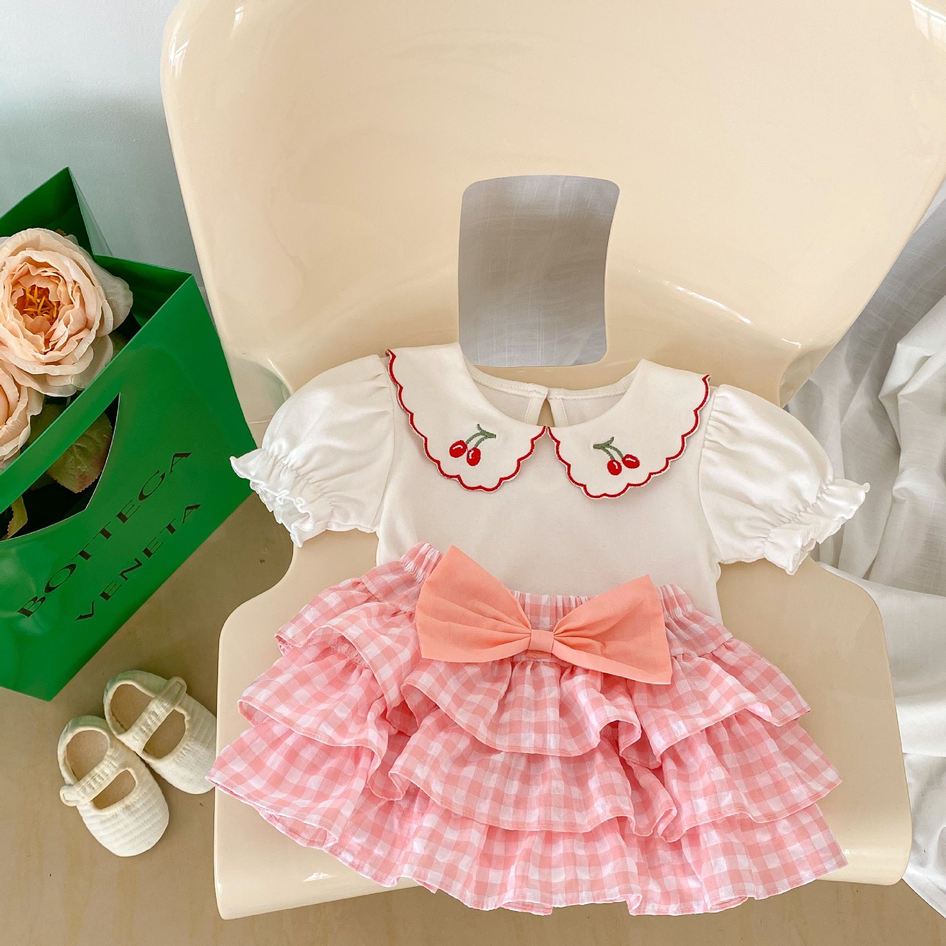 Baby girl outfit featuring a cherry laple neck shirt and plaid skirt, perfect for summer occasions.