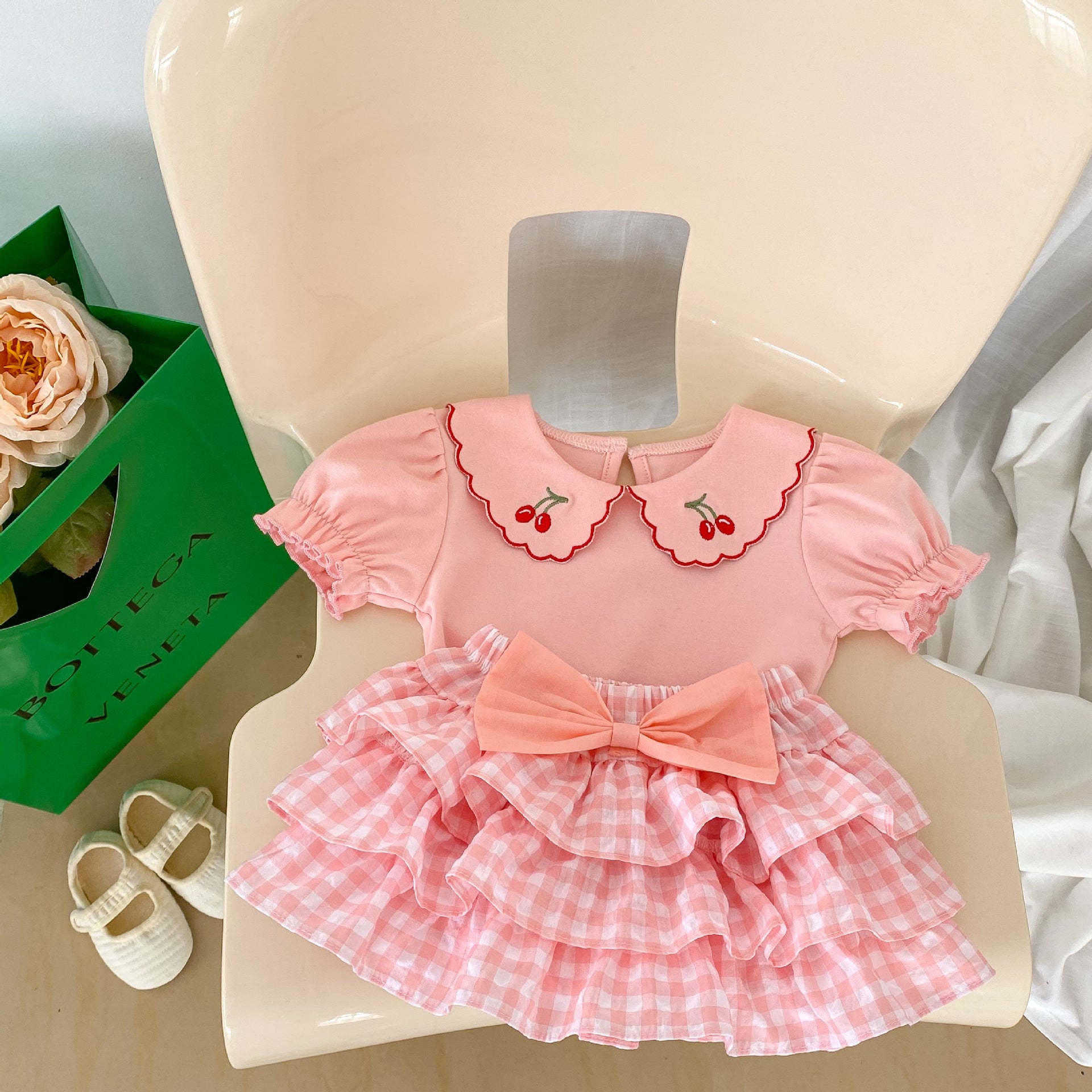 Baby girl outfit featuring a cherry laple neck shirt and plaid skirt, perfect for summer occasions.