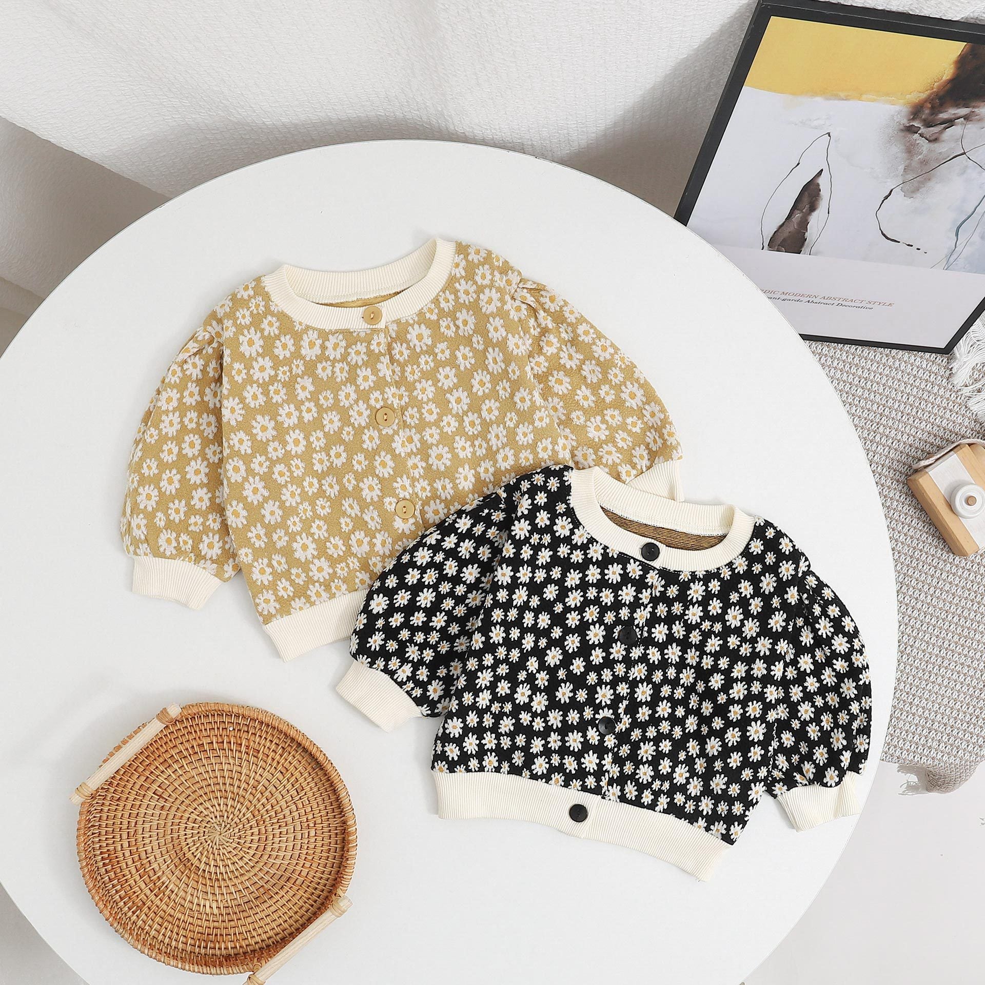 Baby girl cardigan featuring a daisy pattern and puff sleeves, available in black and yellow colors.