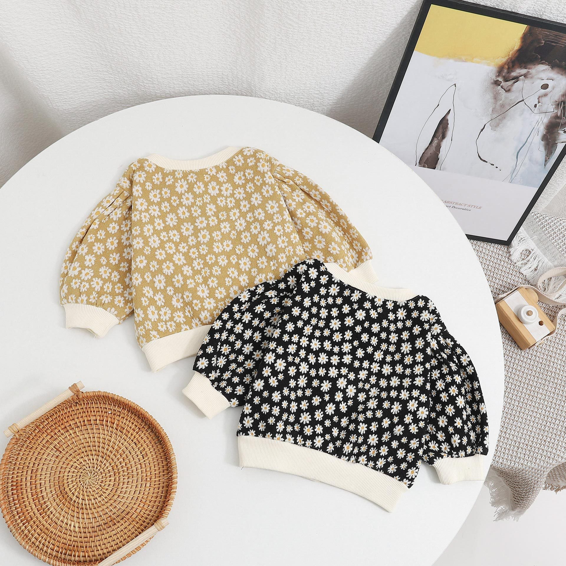 Baby girl cardigan featuring a daisy pattern and puff sleeves, available in black and yellow colors.