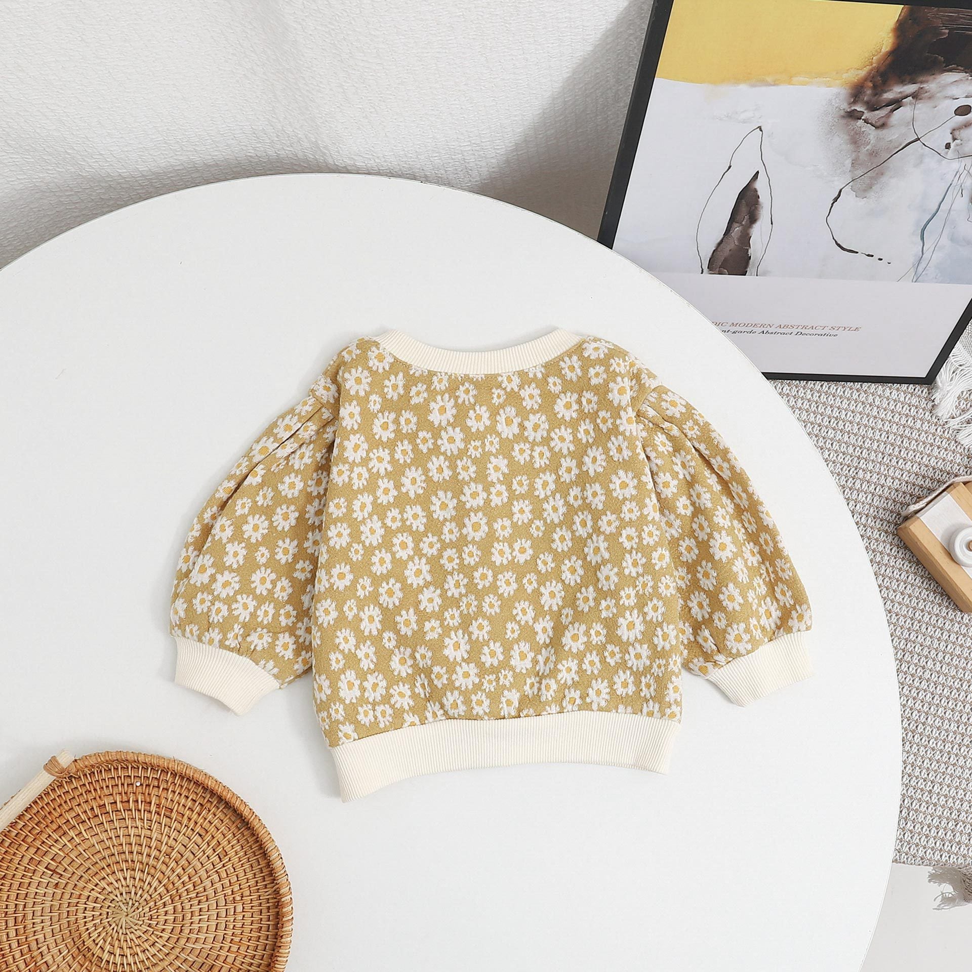 Baby girl cardigan featuring a daisy pattern and puff sleeves, available in black and yellow colors.