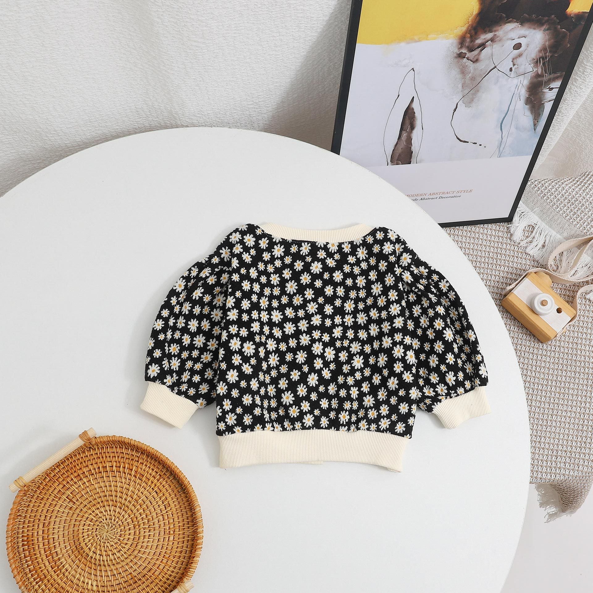 Baby girl cardigan featuring a daisy pattern and puff sleeves, available in black and yellow colors.