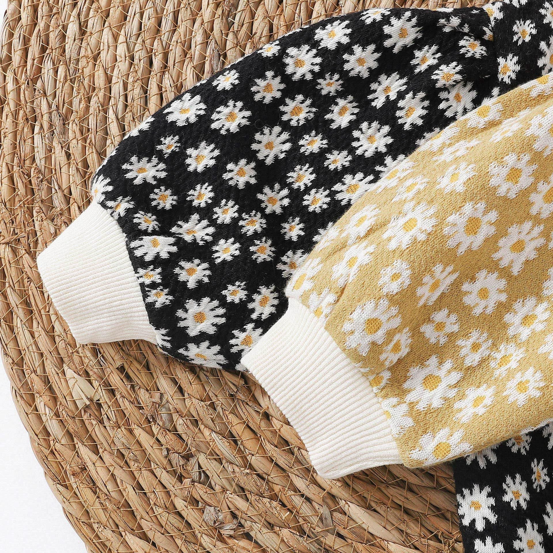 Baby girl cardigan featuring a daisy pattern and puff sleeves, available in black and yellow colors.