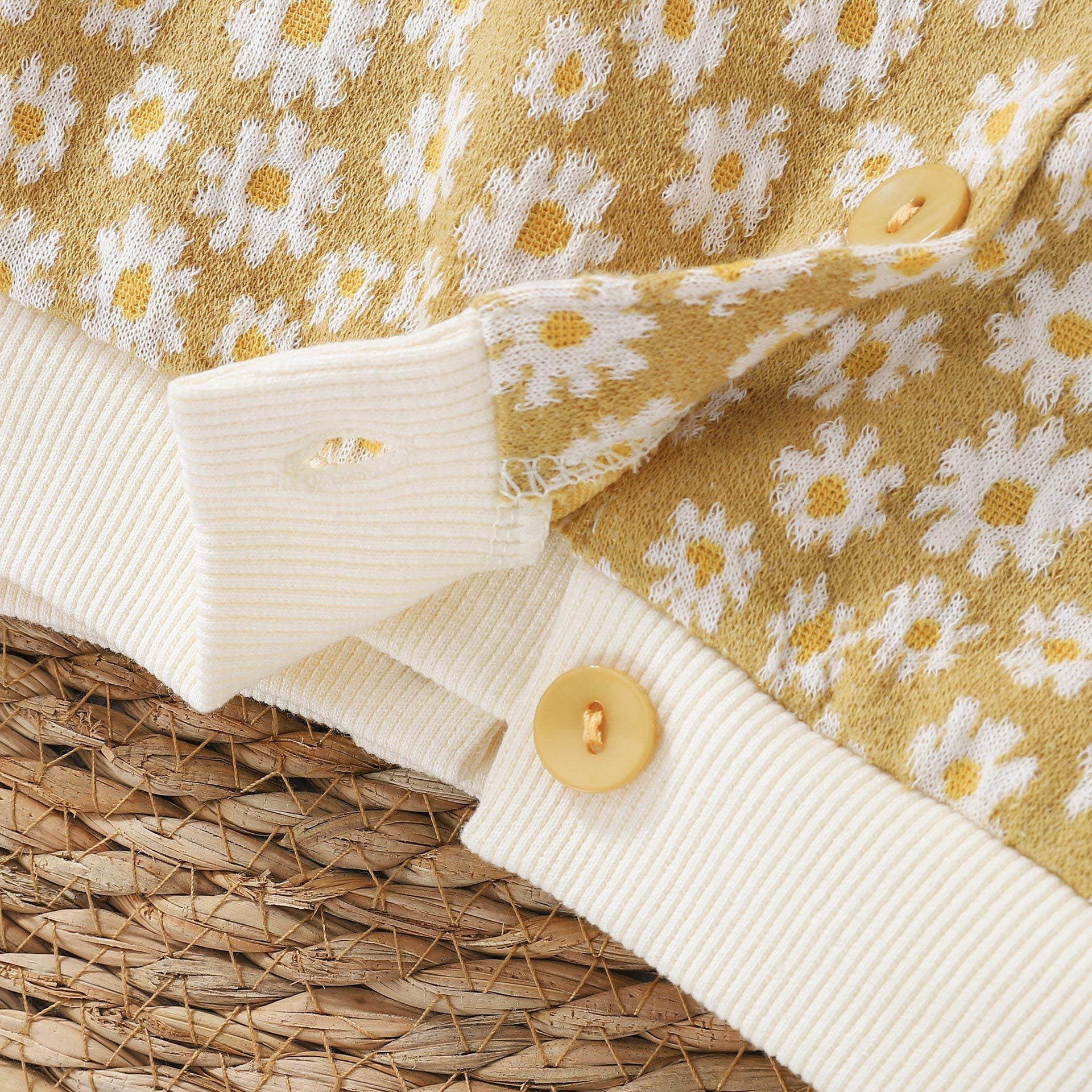 Baby girl cardigan featuring a daisy pattern and puff sleeves, available in black and yellow colors.