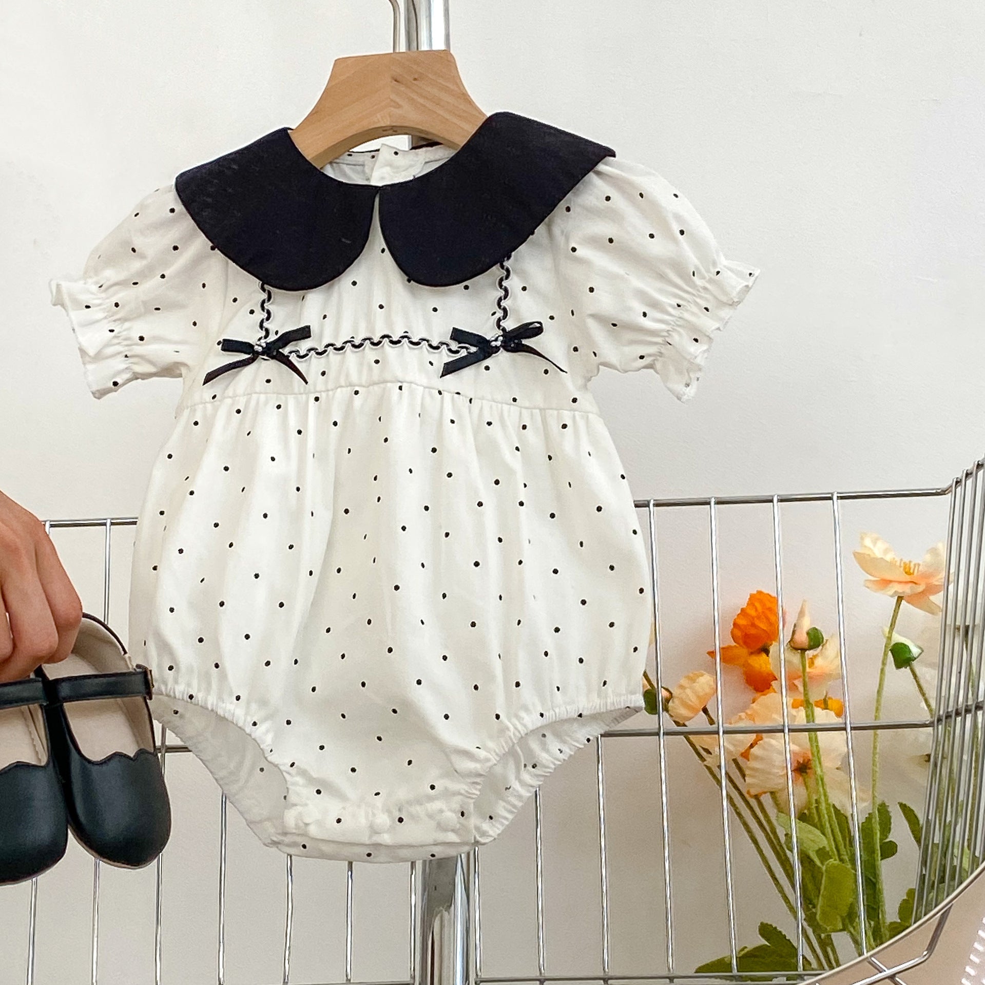 Baby girl onesie featuring a polka dot pattern and doll neck triangle design, perfect for summer wear.