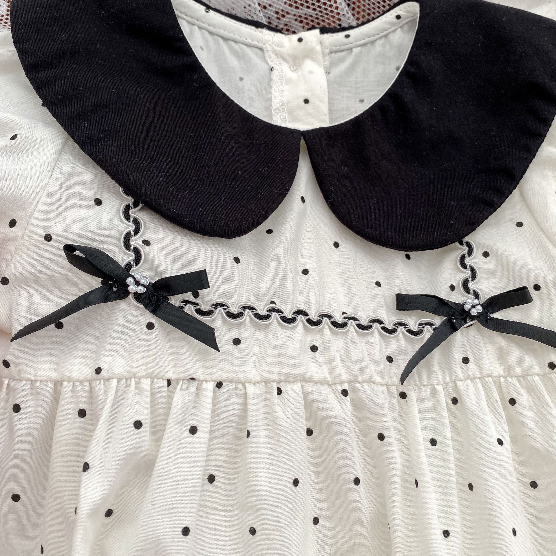 Baby girl onesie featuring a polka dot pattern and doll neck triangle design, perfect for summer wear.